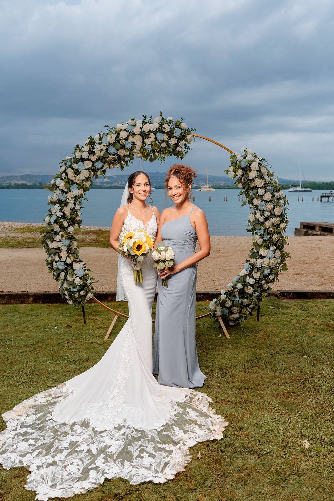 Elegant beach wedding ceremony setup with floral arches and white decor along the shoreline.