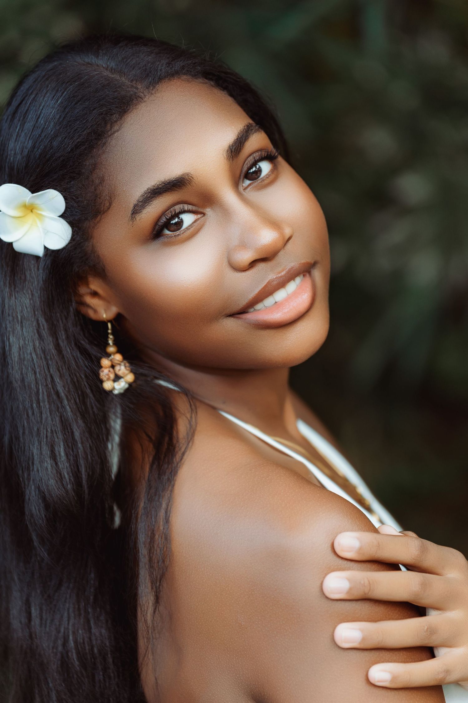 A series of artistic beauty portraits featuring a white plumeria flower accent against a dark background.
