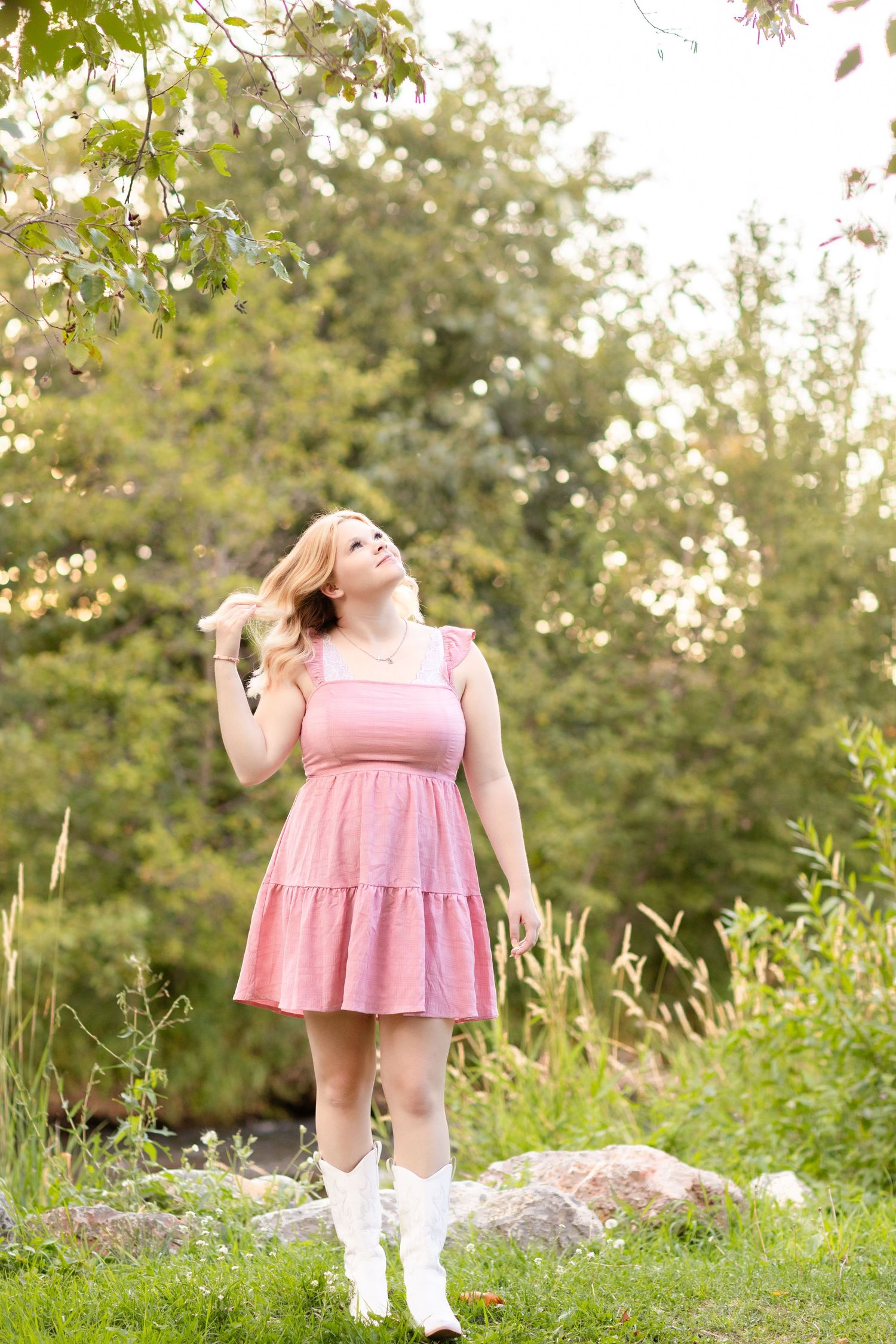 Pink dress twirls in a sunny garden setting with green foliage and wildflowers in the background.