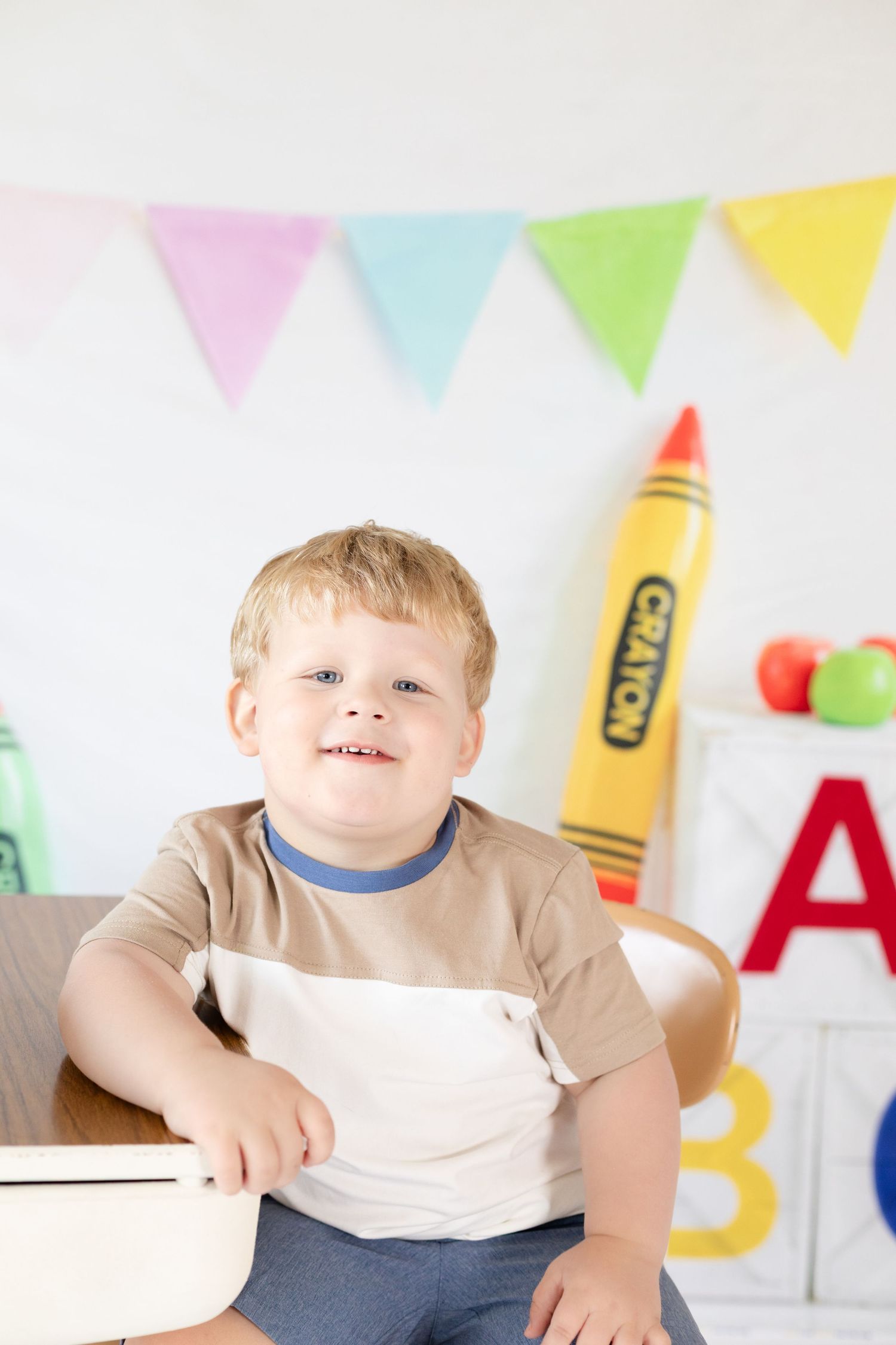 Colorful classroom setting with pastel bunting flags and a large decorative crayon on the wall.