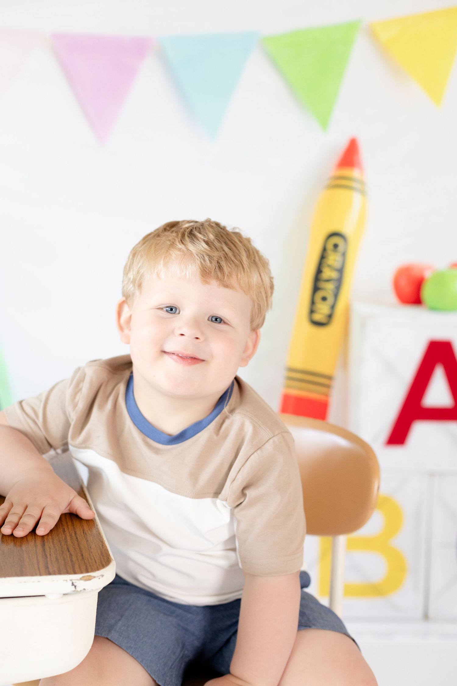 A child sits at a table with colorful party decorations and bunting in the background.