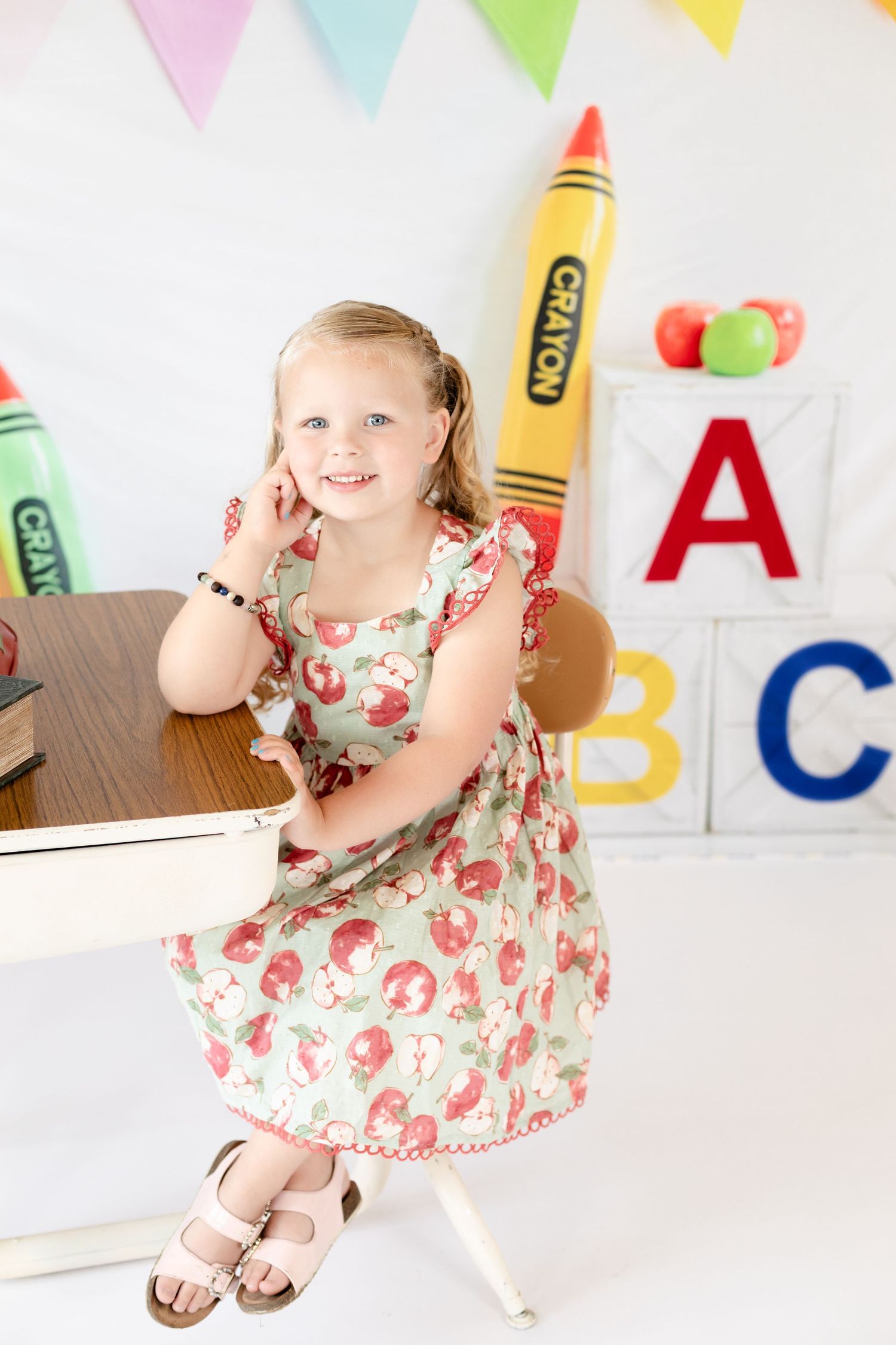Four connected photos showing a child in a floral dress playing and posing in a colorful classroom setting with ABC decorations.