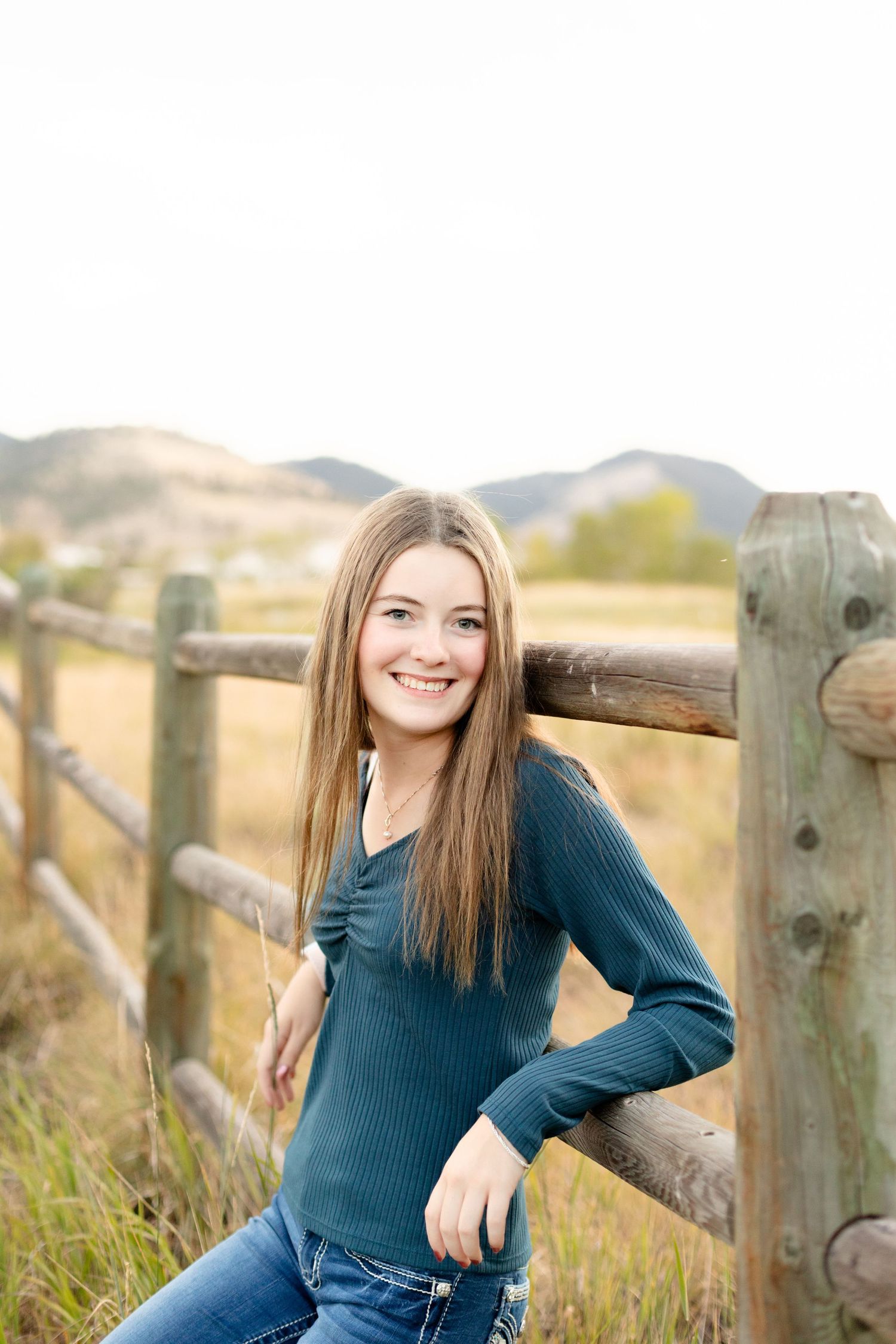 Senior portrait photography featuring casual poses by a rustic wooden fence in golden afternoon light.