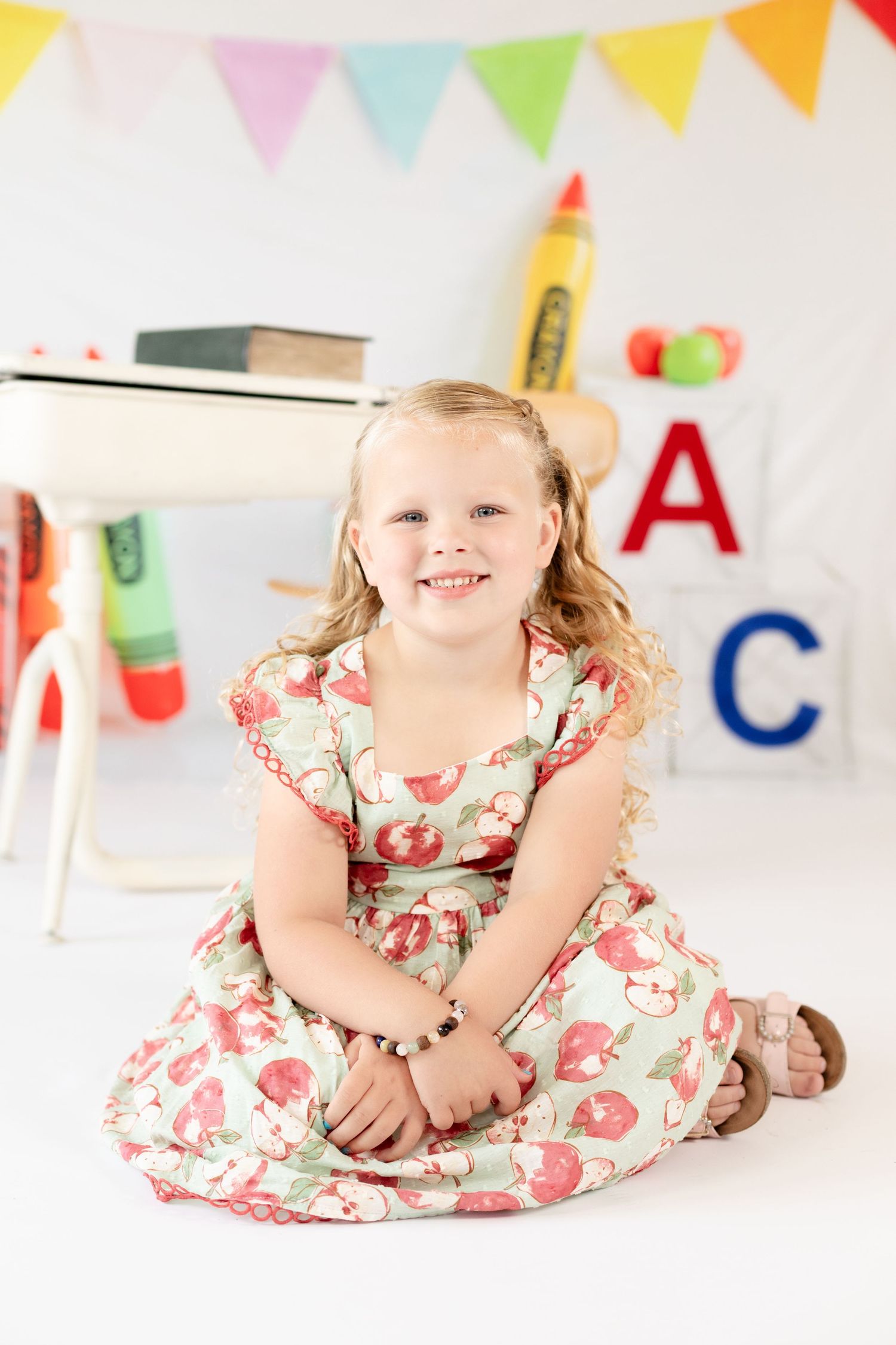 Colorful birthday party scene with bunting decorations and a child wearing a floral dress lying on the floor.