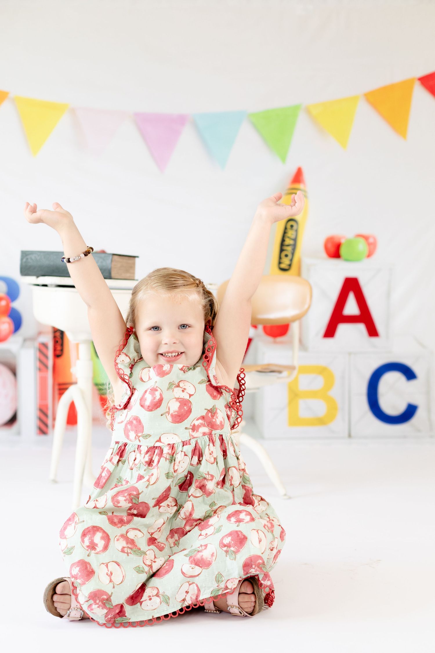 A floral dress against a white backdrop with ABC letters and rainbow bunting decorations overhead.