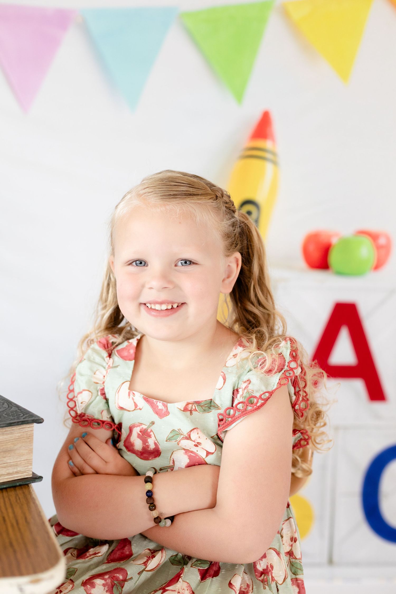 A child in a floral dress smiles during a colorful birthday party with bunting decorations in the background.