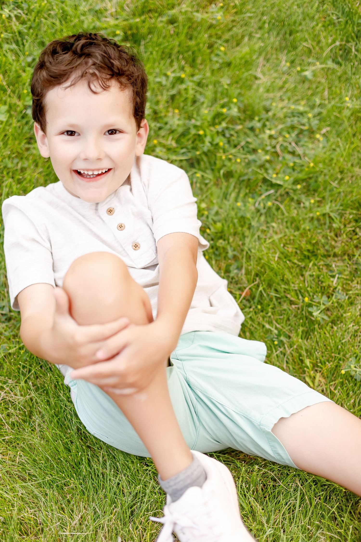 Candid outdoor shots of child playing on grass in white and mint outfit on sunny day.
