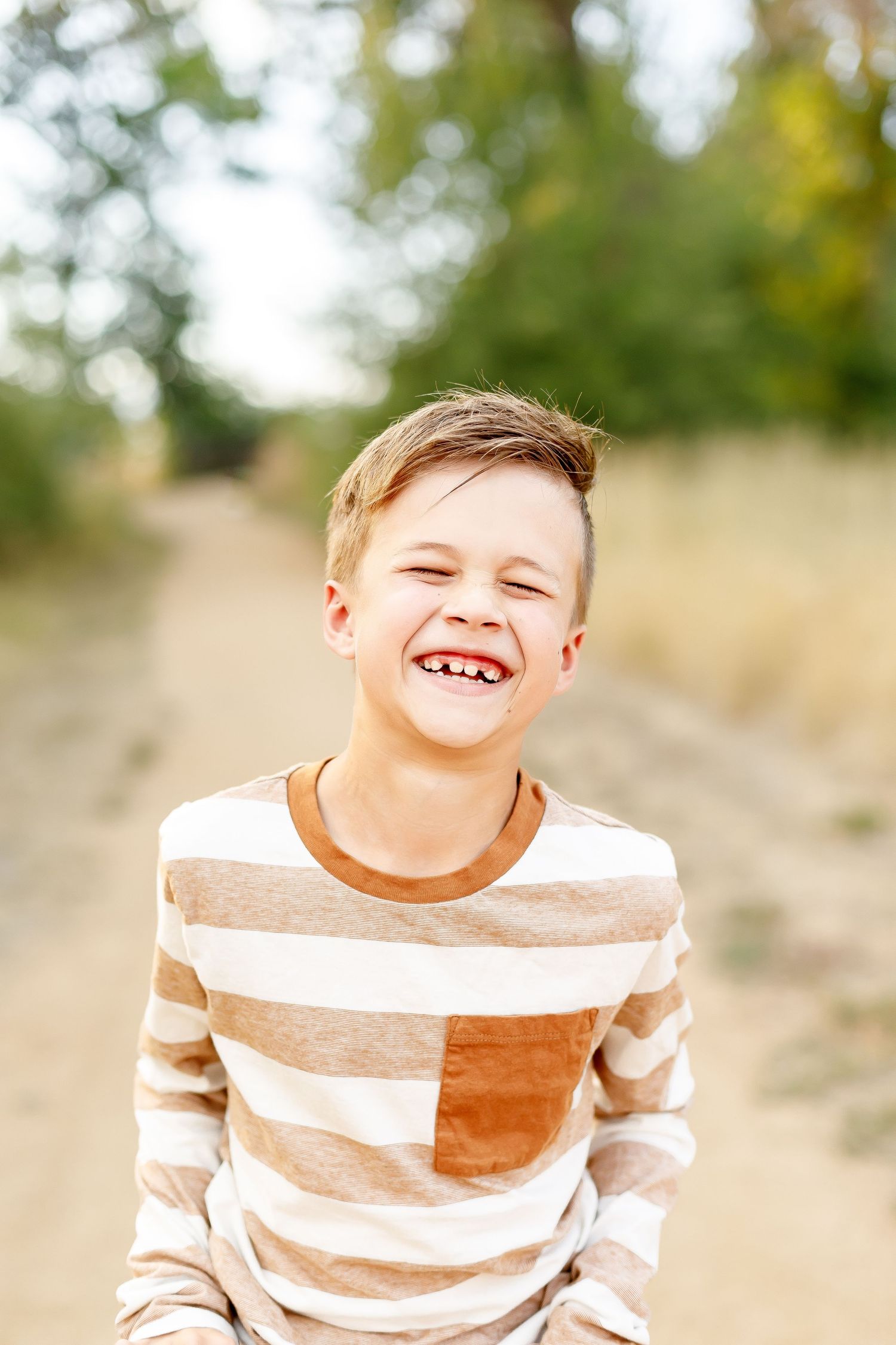 Four sequential photos of a joyful child in a beige striped sweater expressing increasing happiness outdoors.