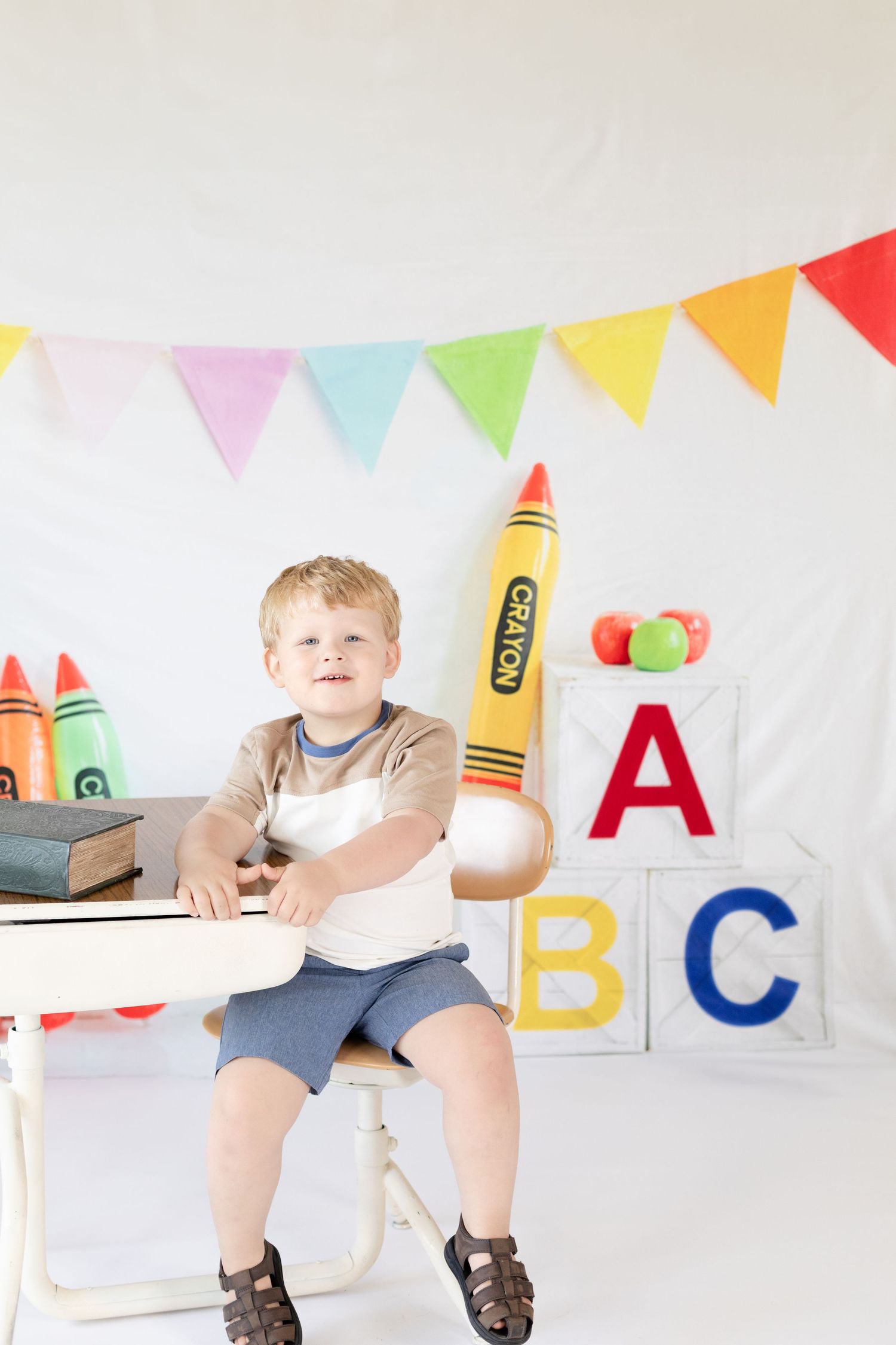 Colorful classroom setup with ABC blocks, crayon decorations and festive bunting flags against white background.