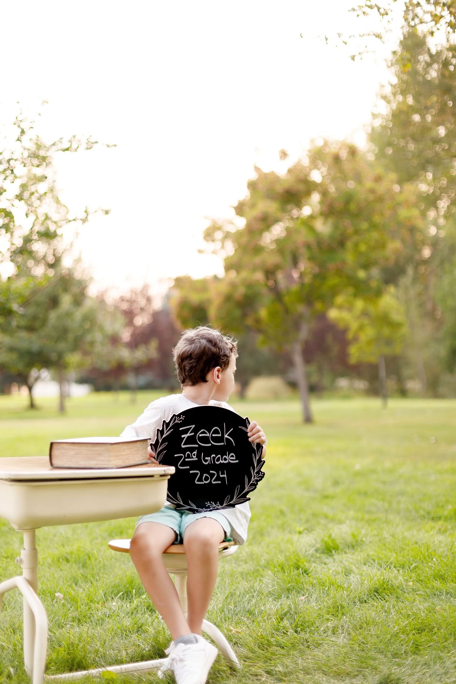 Series of photos showing child at school desk in grassy field during sunset.