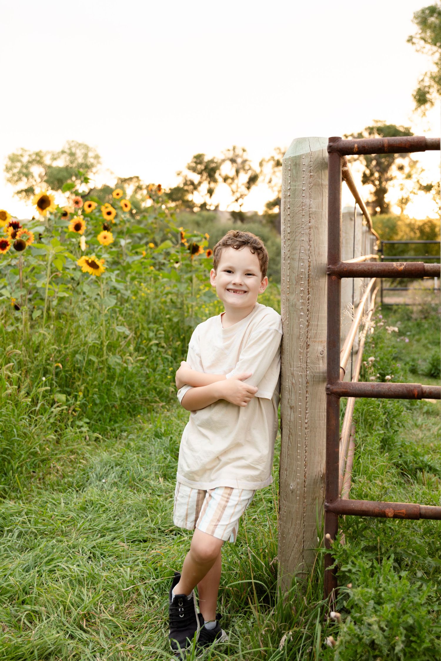 A child stands joyfully in a vibrant field of blooming sunflowers during golden hour.