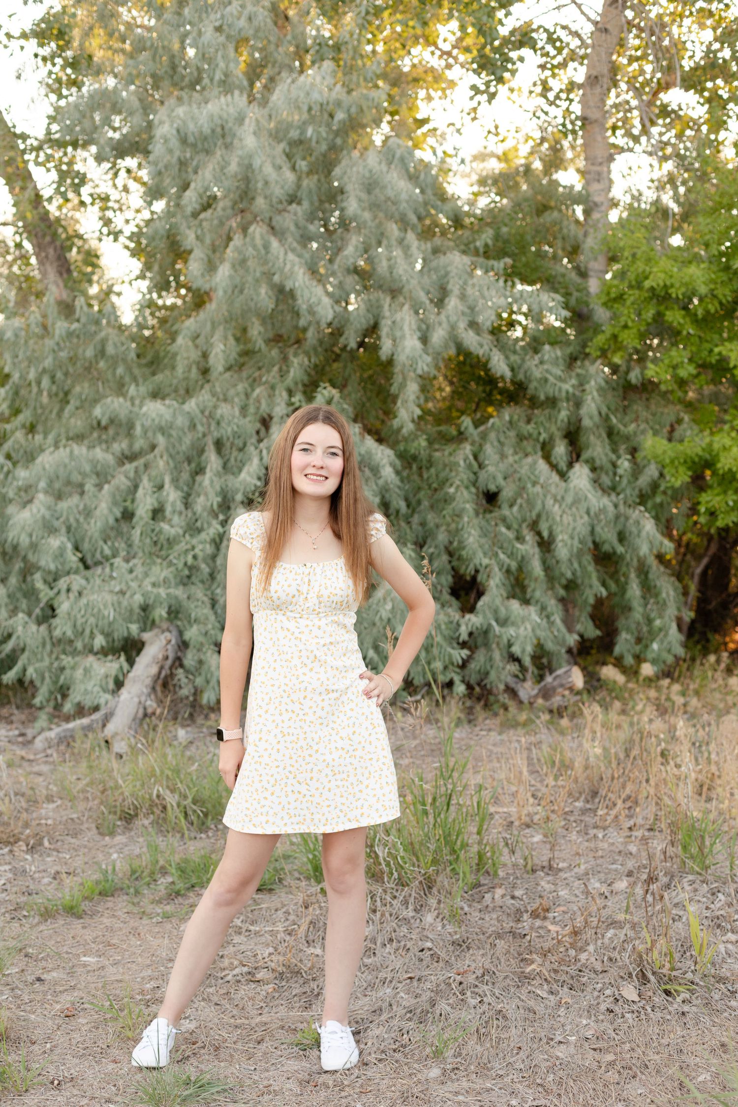 Playful poses captured against silvery evergreen trees in natural outdoor setting.