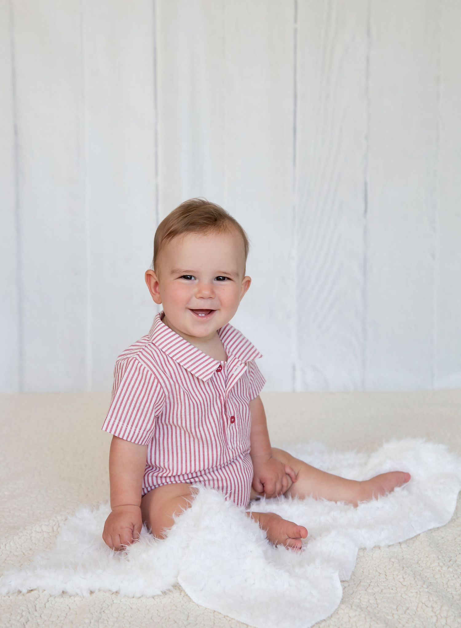 6 month old baby in romper grinning happily at the camera. In-home studio photoshoot in Mt Barker SA.