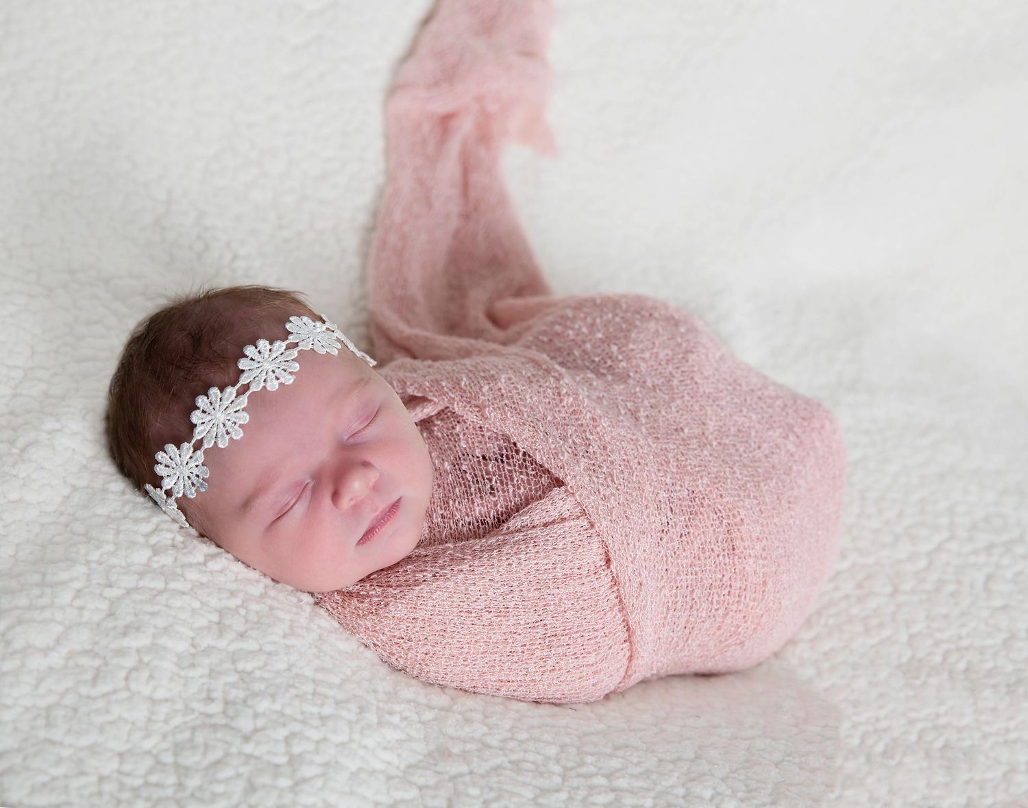 Newborn baby in a pink wrap with a daisy headband. In-home newborn photoshoot in Adelaide SA.