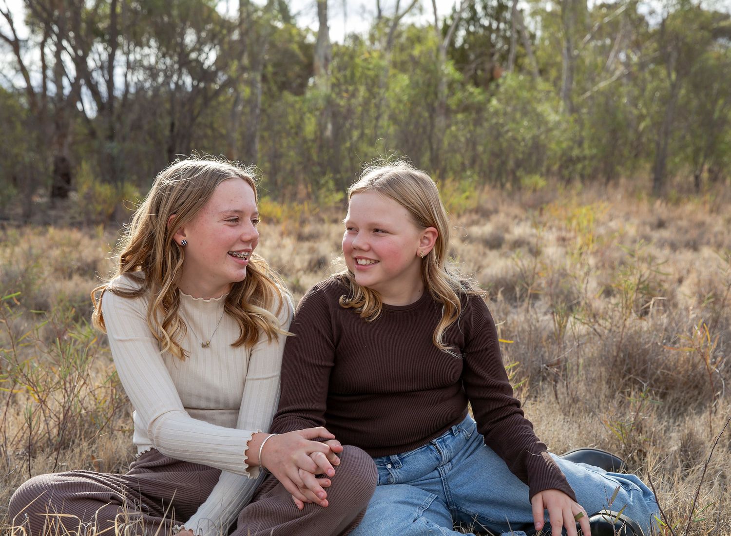 Older children, sisters, in neutral outfits, smiling at each other, family photography in Virginia SA.
