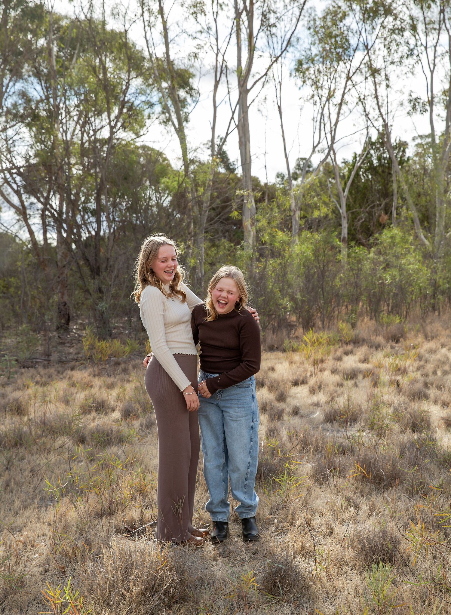 Two sisters casually laughing together, natural photography poses in reserve in Adelaide SA.