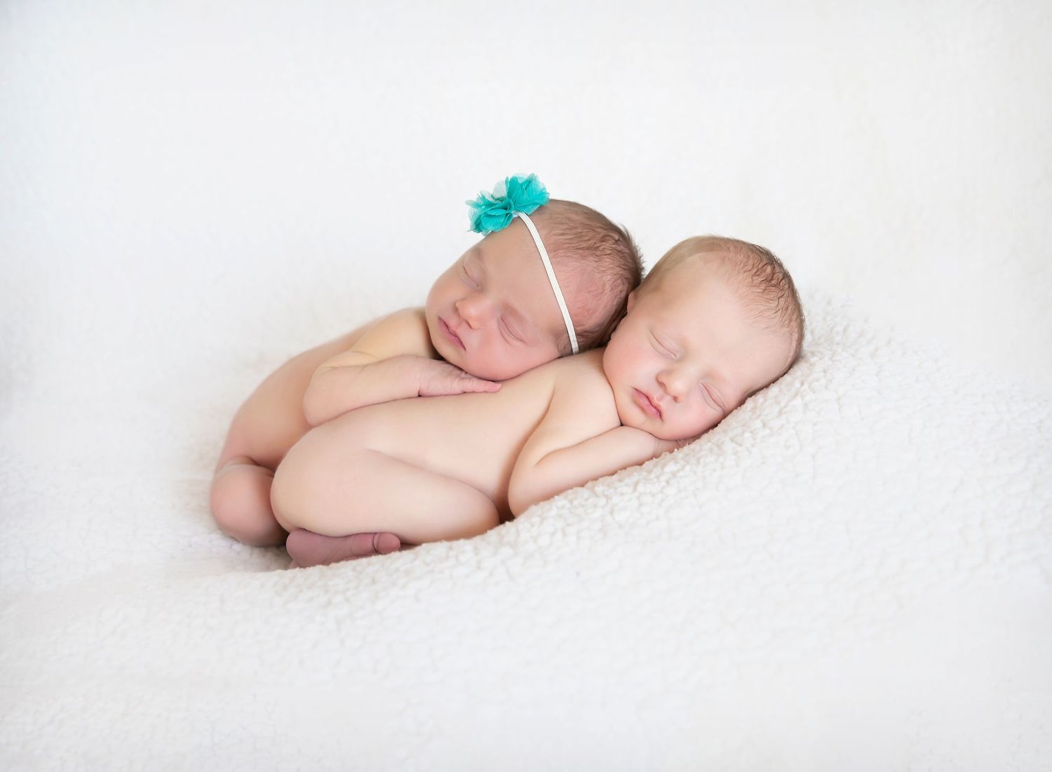 Newborn twins, boy and girl, laying on their tummies, cuddled up together sleeping soundly in home newborn photo shoot.