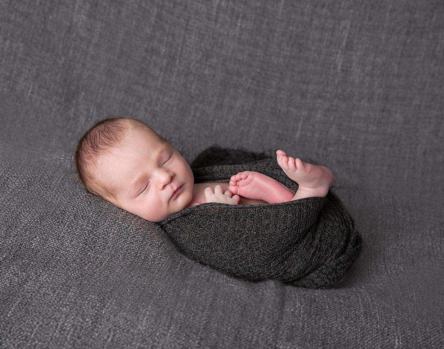 newborn baby boy posed in grey knit wrap sleeping for in home newborn photography session
