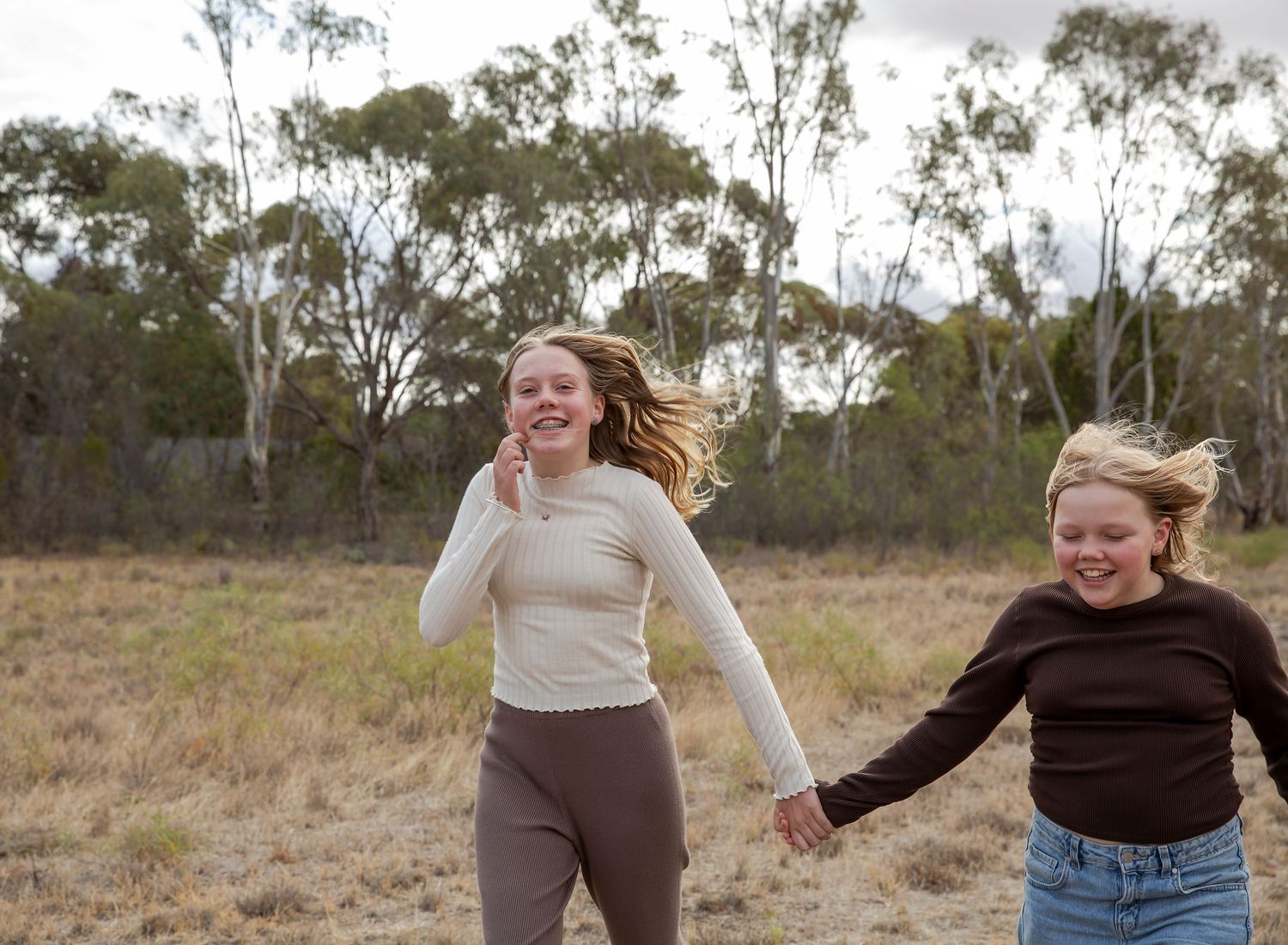 Two sisters playfully running and smiling in documentary style family photoshoot in Virginia SA.