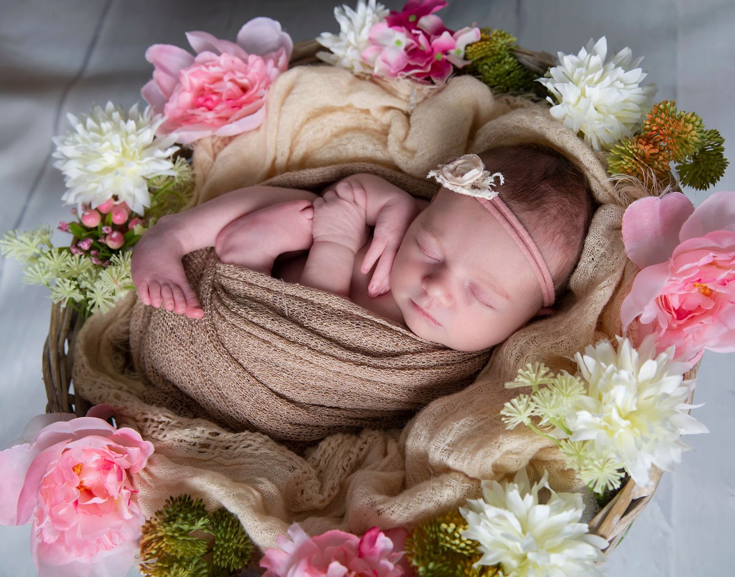 newborn baby girl posed in floral basket for in-home newborn session at home
