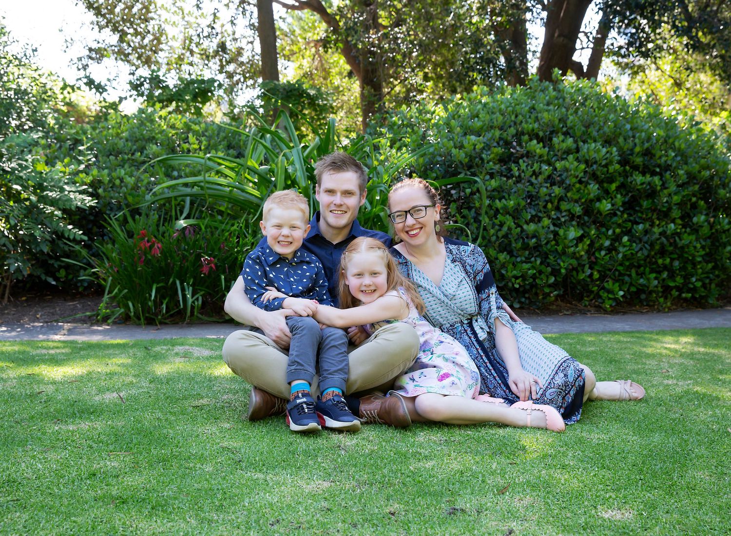 happy family cuddles in close with big smiles for outdoor family photoshoot in the Himenji Gardens
