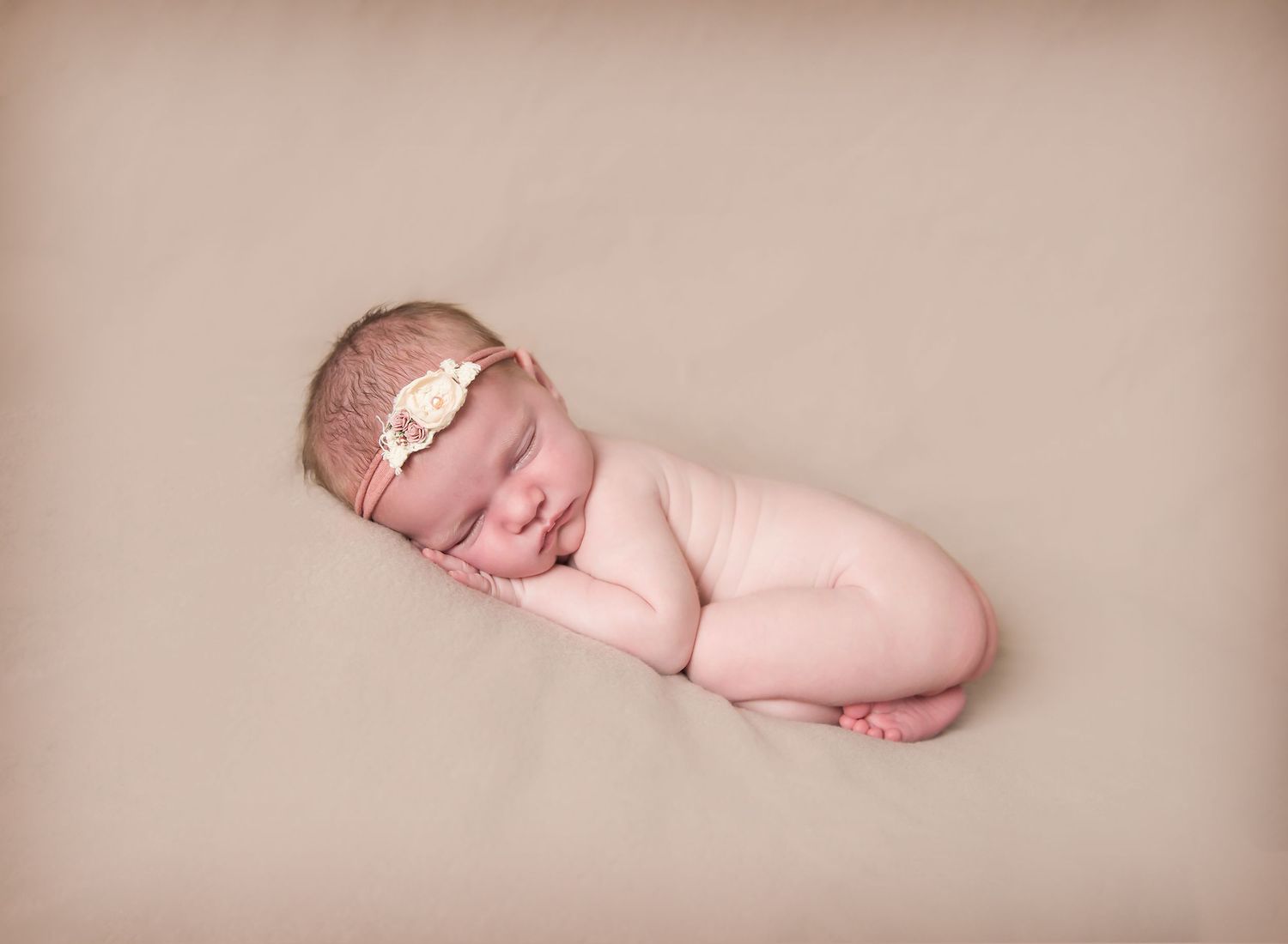 Newborn baby in bottom up pose with floral headband. Sleeping peacefully. In-home newborn photoshoot in Adelaide SA.