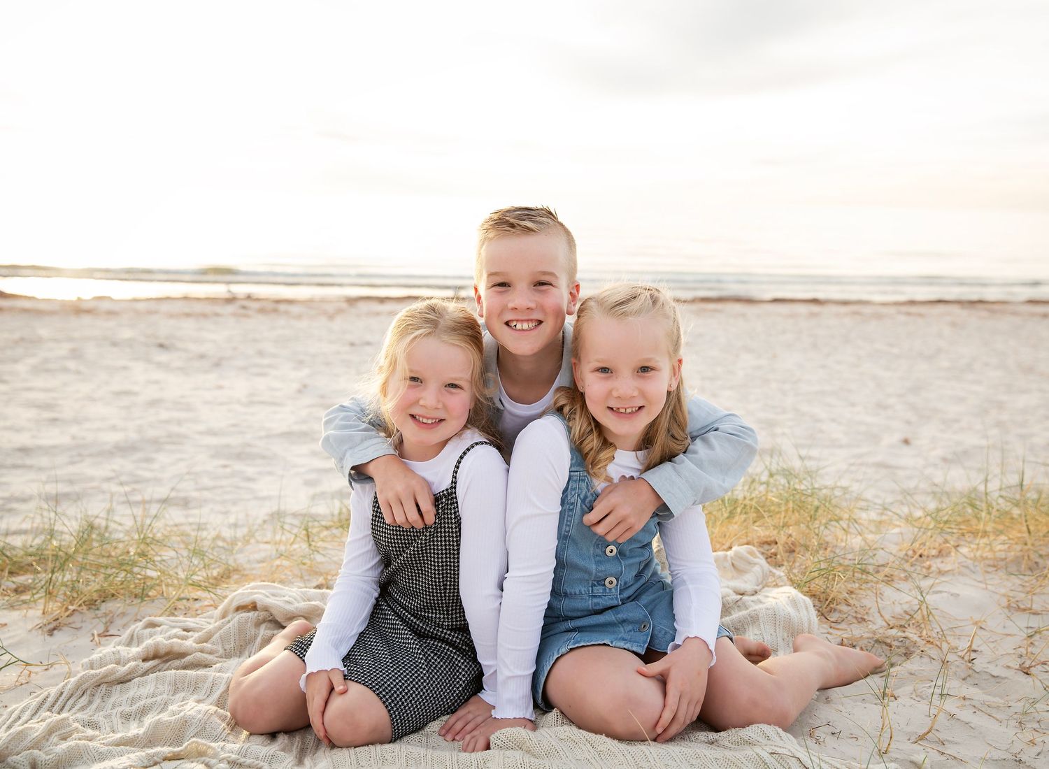 Three siblings cuddling in golden hour sunset beach photoshoot at Largs Bay SA.