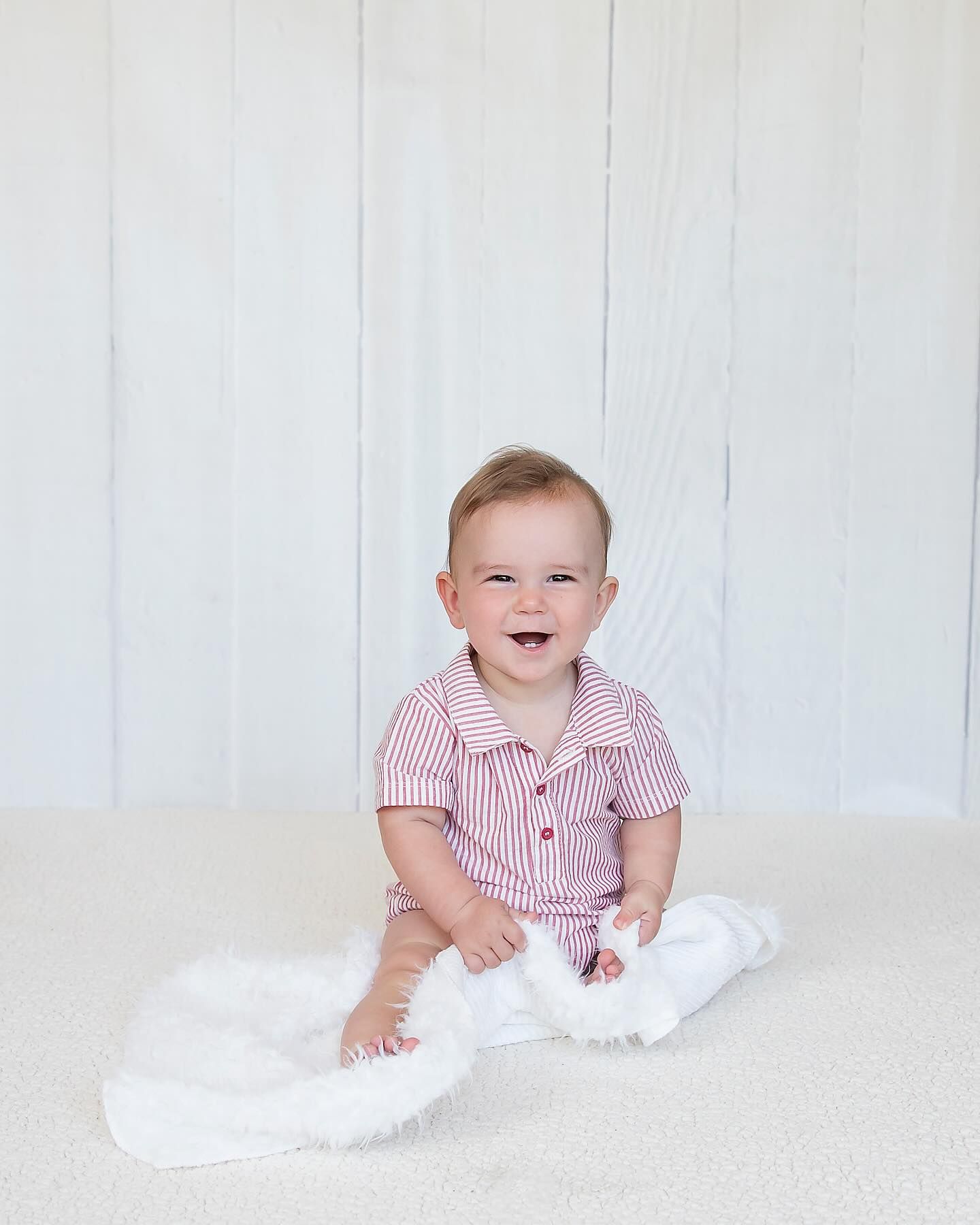 6 month old baby sitting up and smiling at the camera