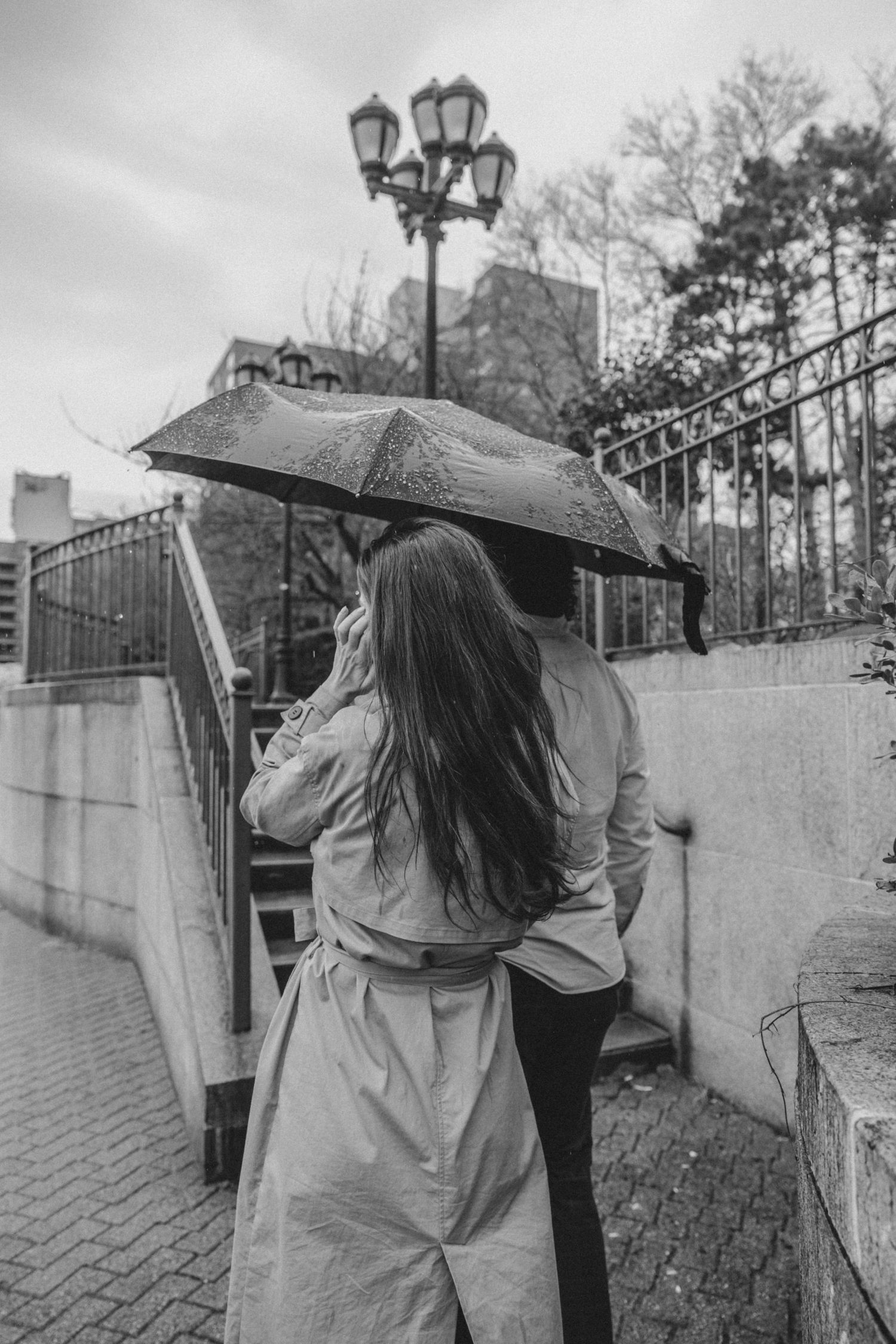 Candid photo of couple in Queens on a rainy afternoon with black umbrella