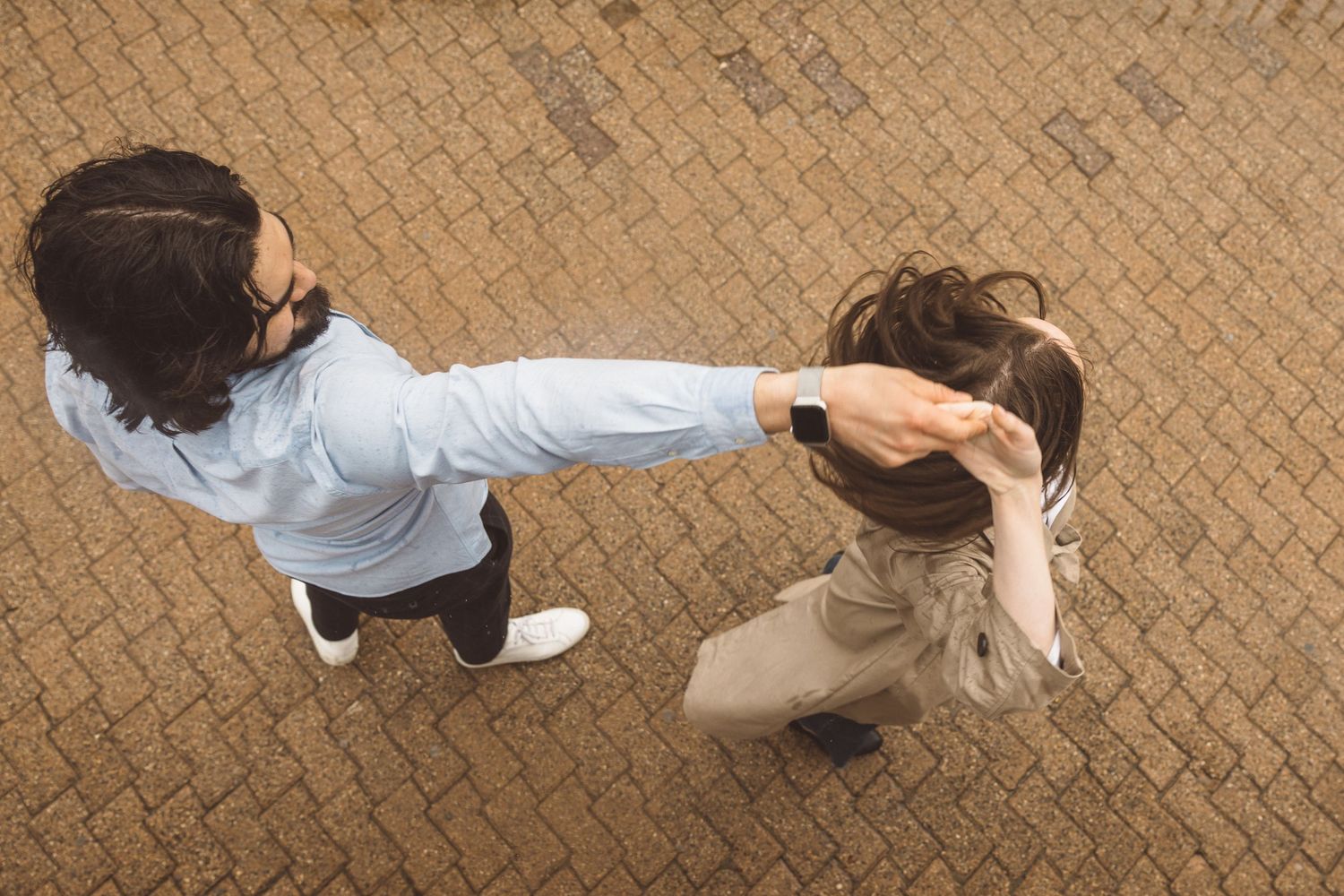 Playful engagement photo of couple dancing in the rain, captured in NYC