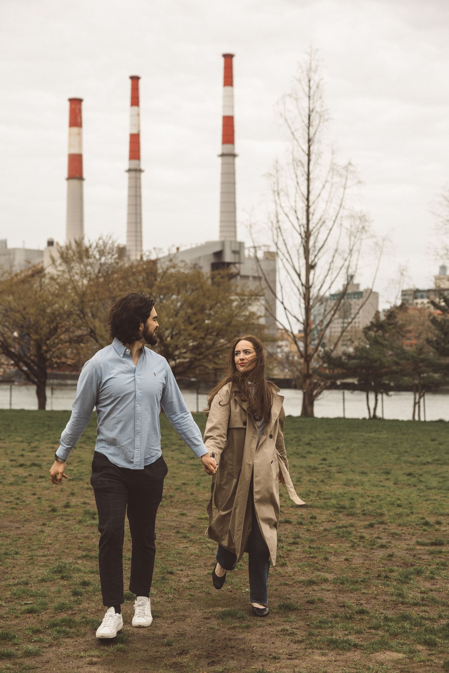 Candid moment of couple running through a grassy field in Queens, NYC