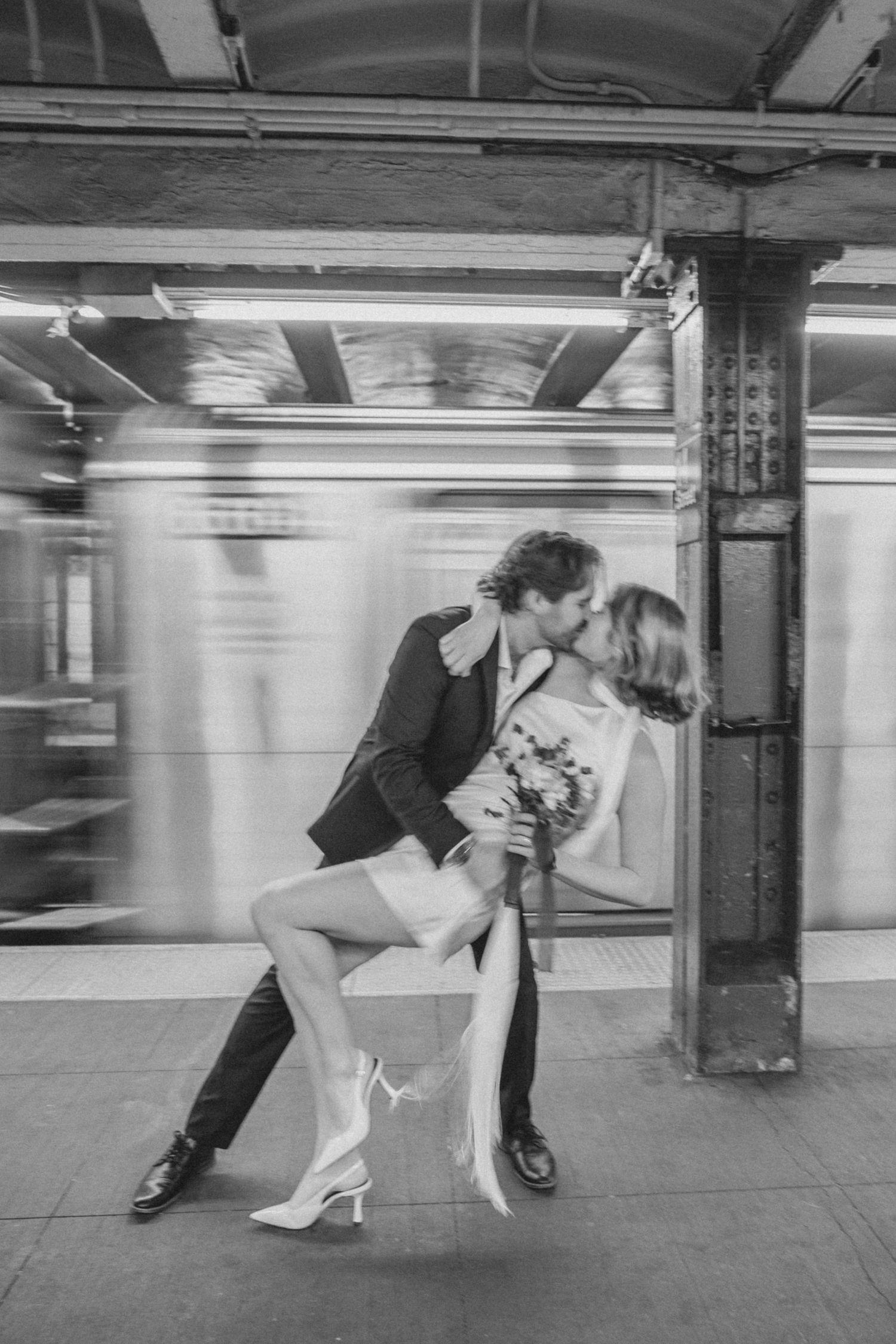 Newlyweds sharing a moment by a passing subway in New York City after City Hall wedding