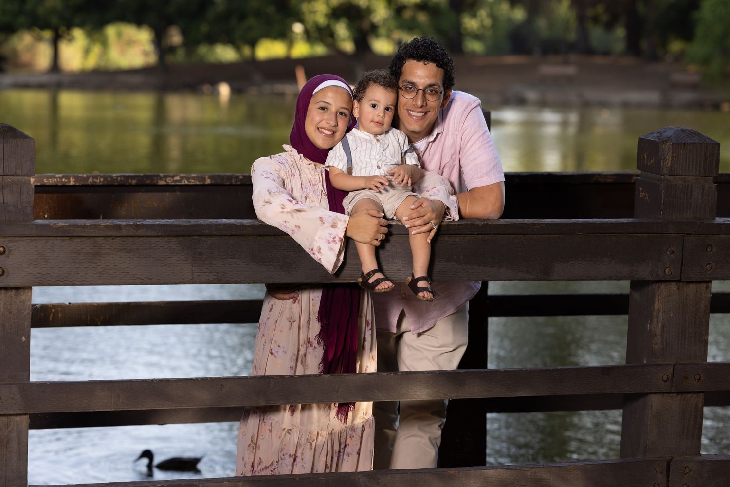 Muslin family of three, posing with their toddler during photo session at Woodward park in Fresno California.
