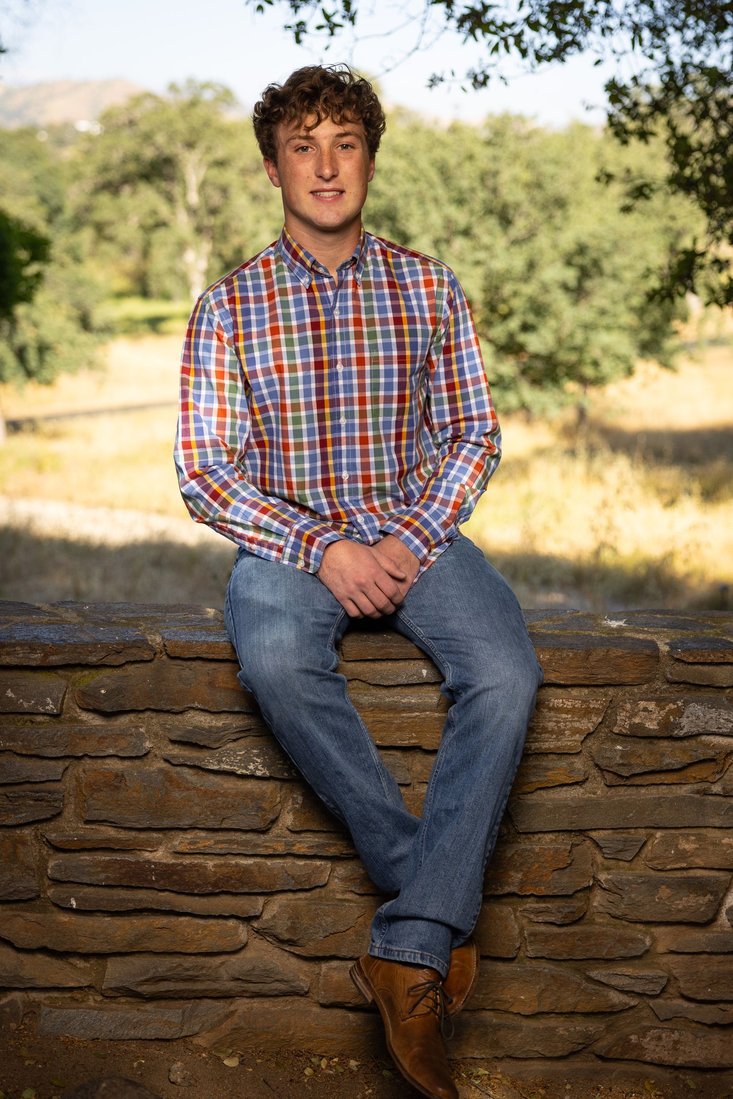 High school senior wearing a checkered shirt and jeans in Clovis California.