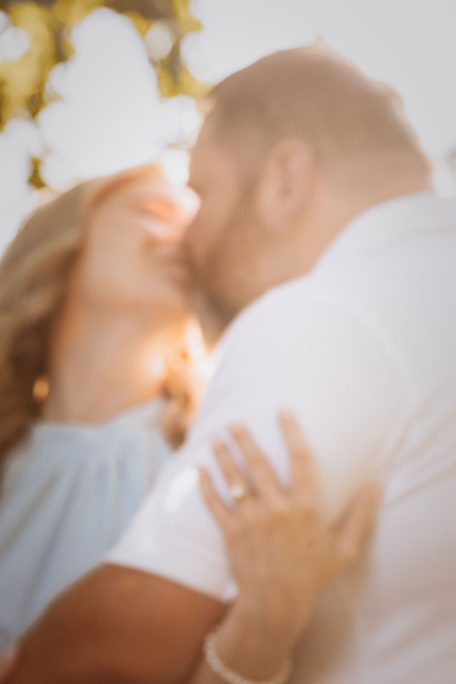 Soft focus artistic photo of romantic couple embracing in golden sunlight.