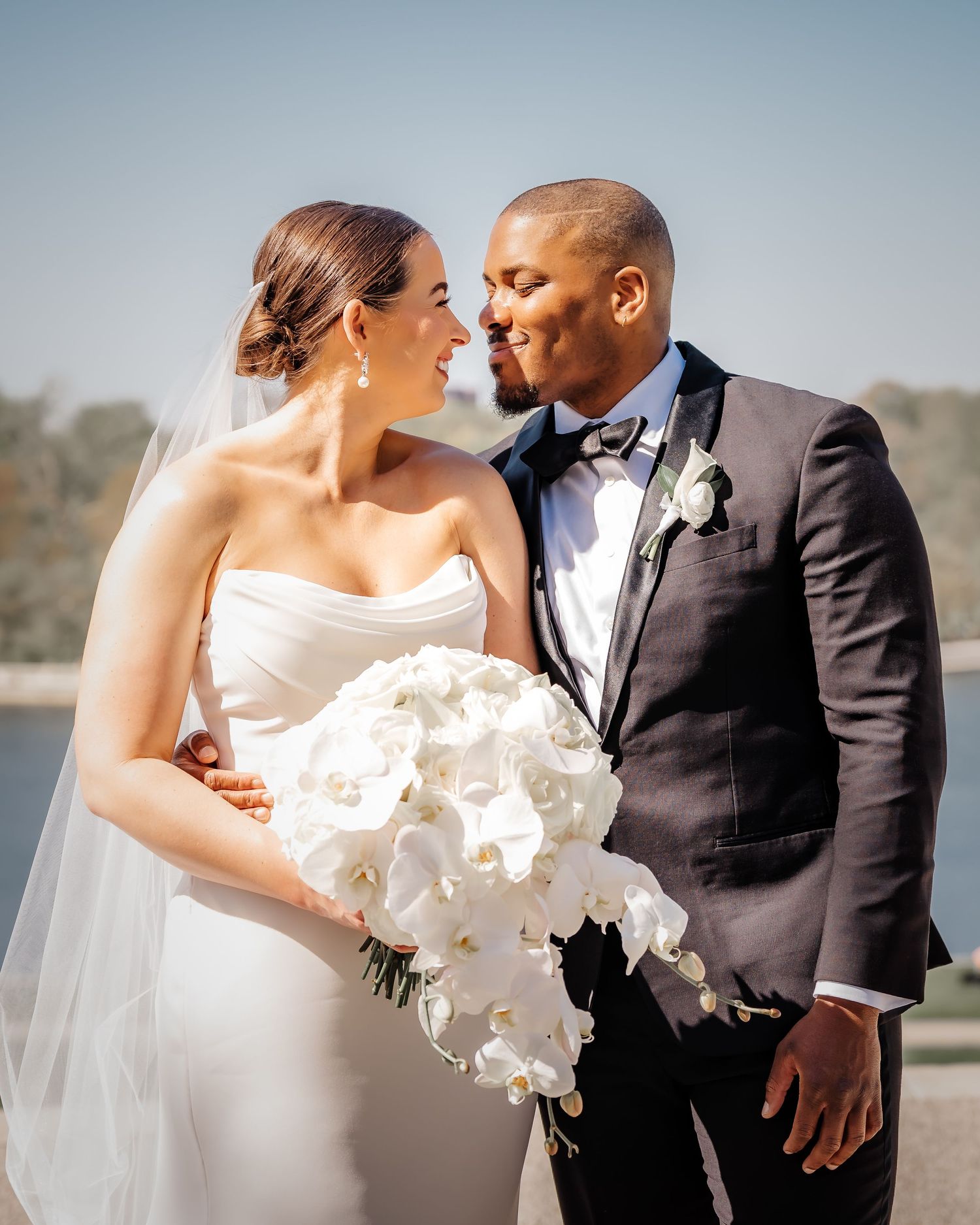 Romantic wedding photo featuring newlyweds with a cascade of white orchids.