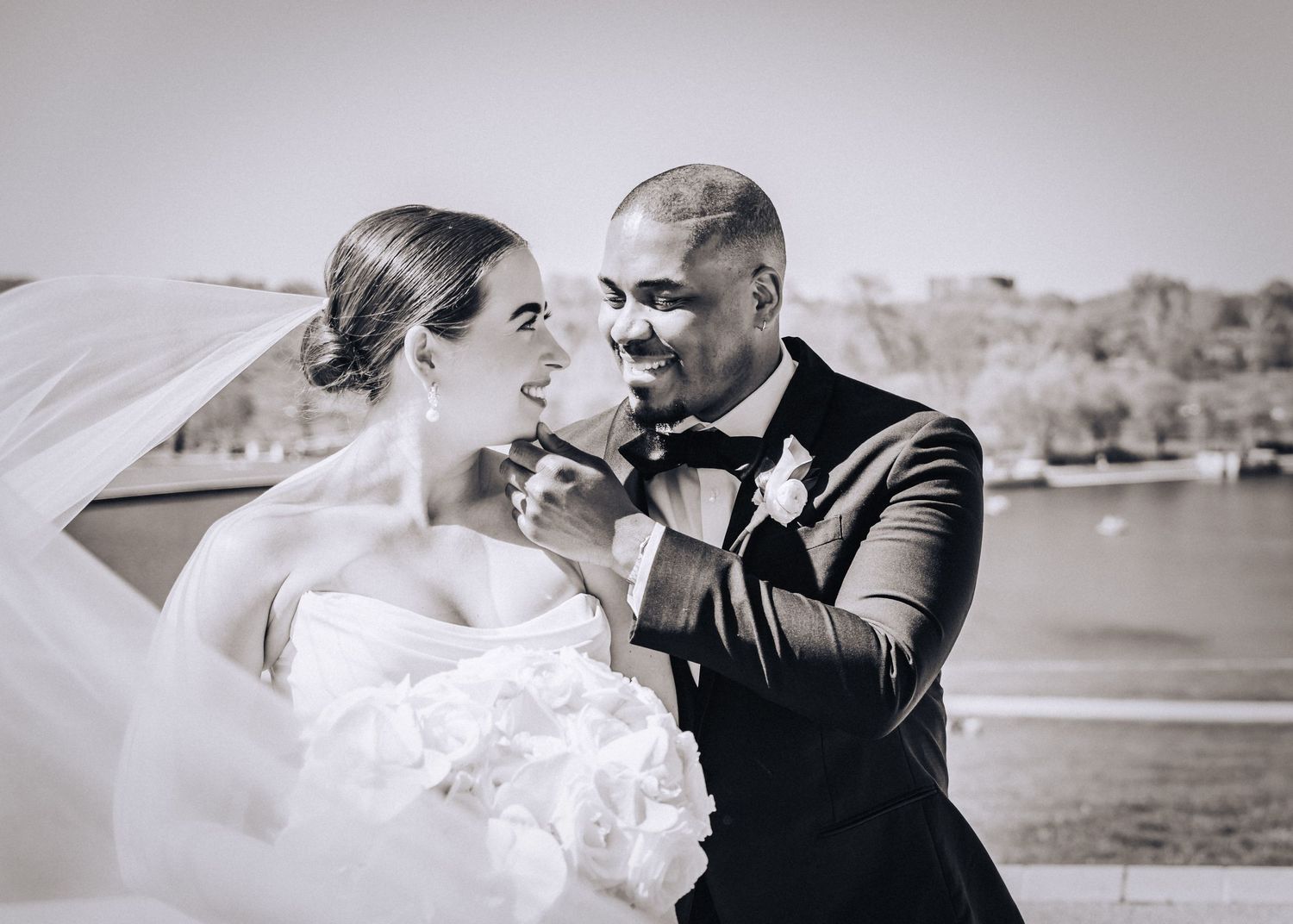 Black and white wedding photo of a couple sharing an intimate moment by the water.