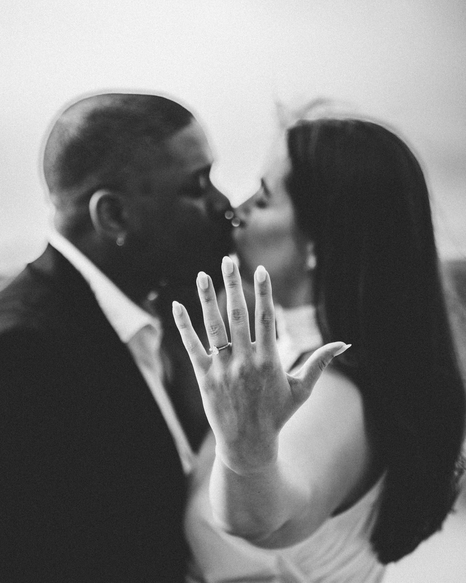 Black and white engagement photo showing ring while couple shares intimate moment.