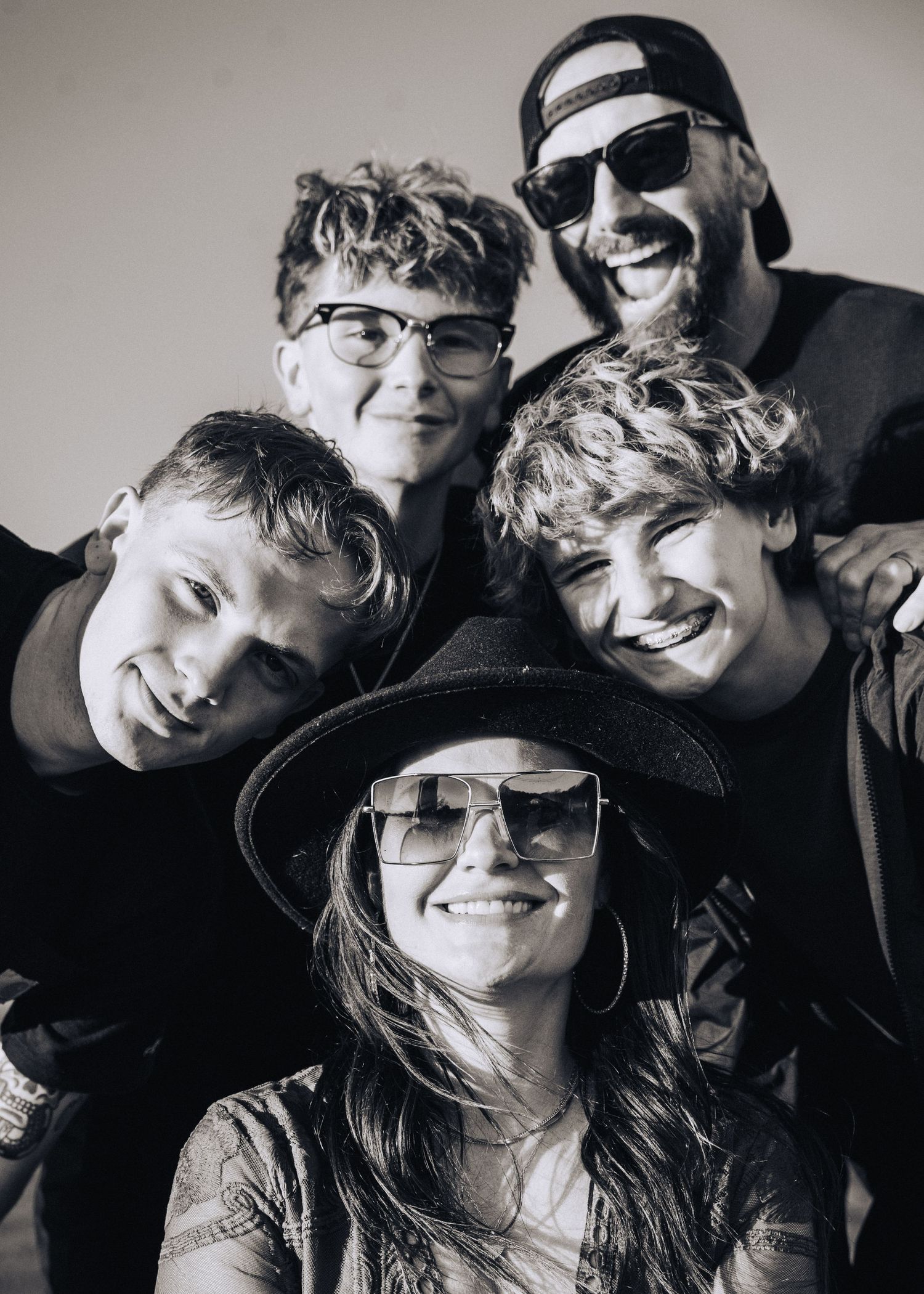 Black and white group selfie of friends smiling and posing together wearing casual accessories.