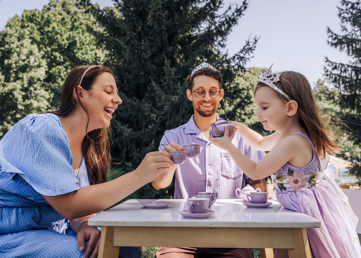 Family enjoying teatime together at outdoor table during summer afternoon.