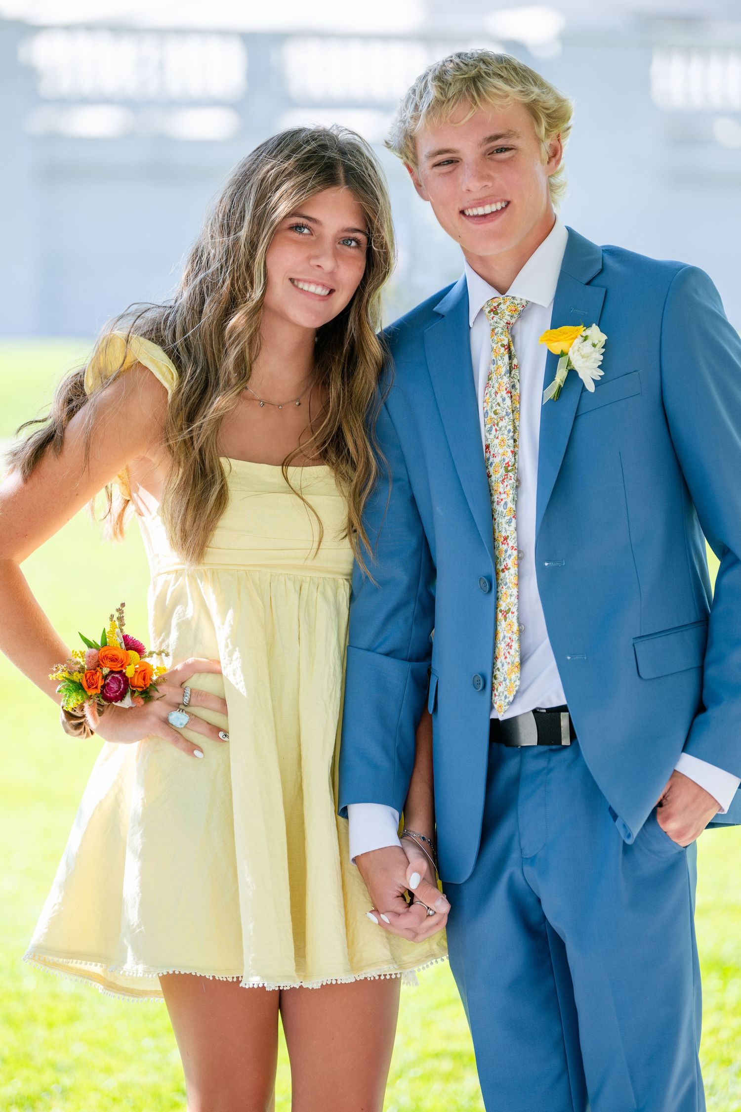 Couple smiling together outdoors with yellow dress and blue suit in bright light