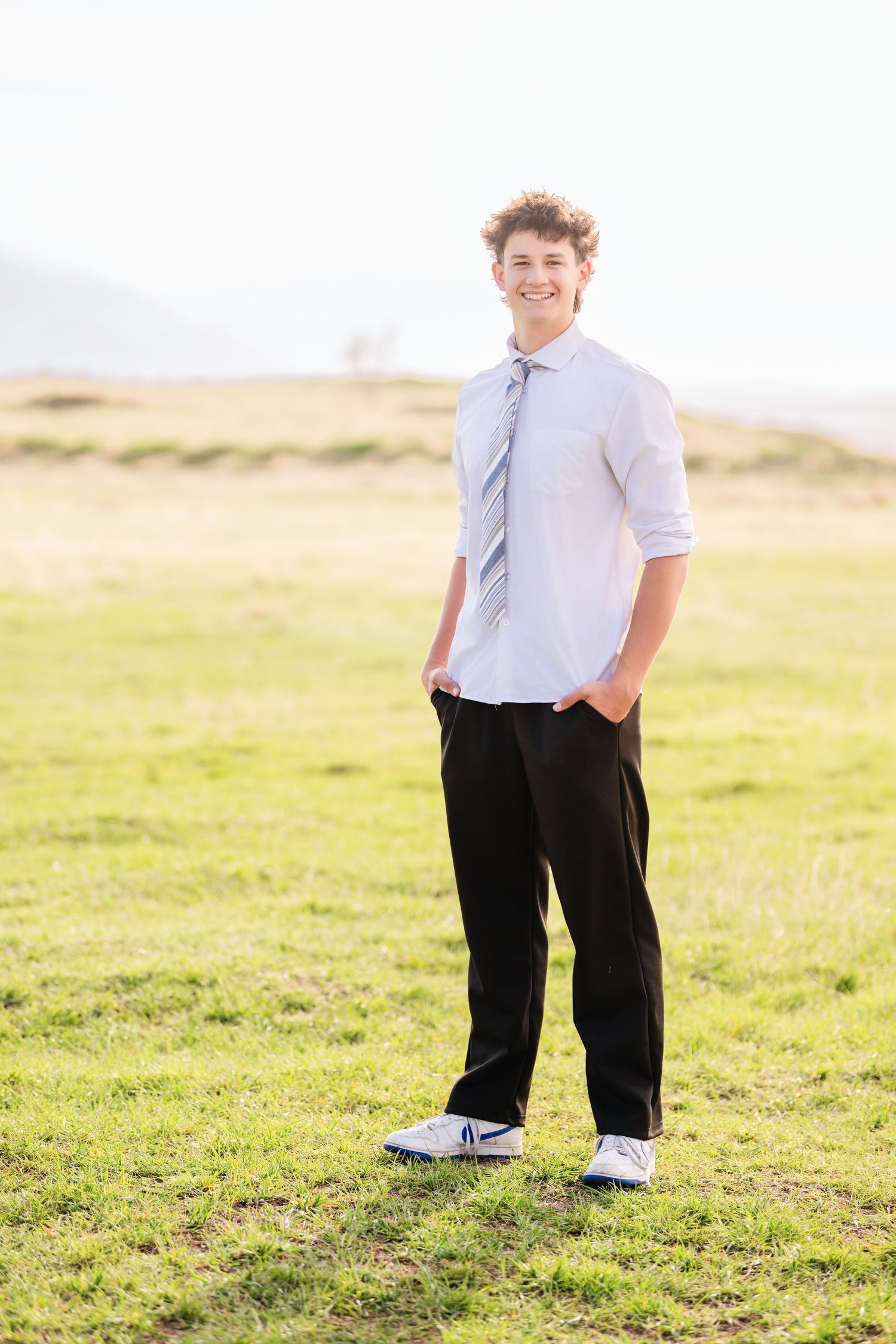 Casual male senior portrait in open grassy field during Utah outdoor senior photography session