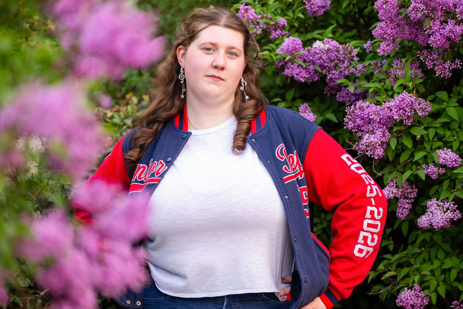 Senior girl portrait surrounded by purple flowers during outdoor Class of 2026 photo session