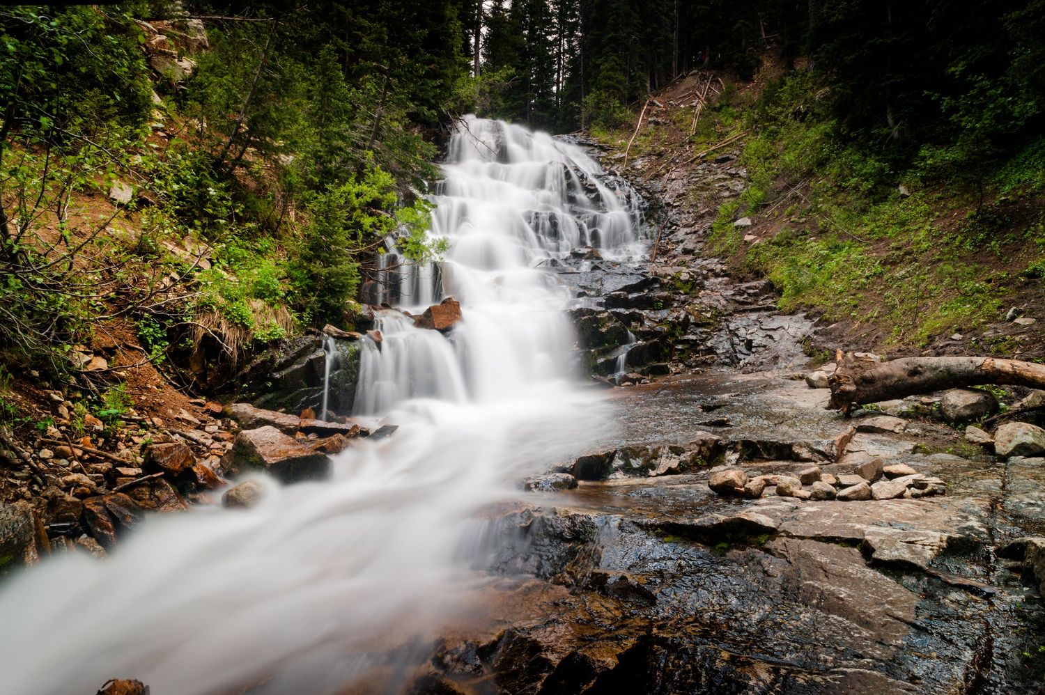 Waterfall in Little Cottonwood Canyon Utah with flowing water and lush forest landscape