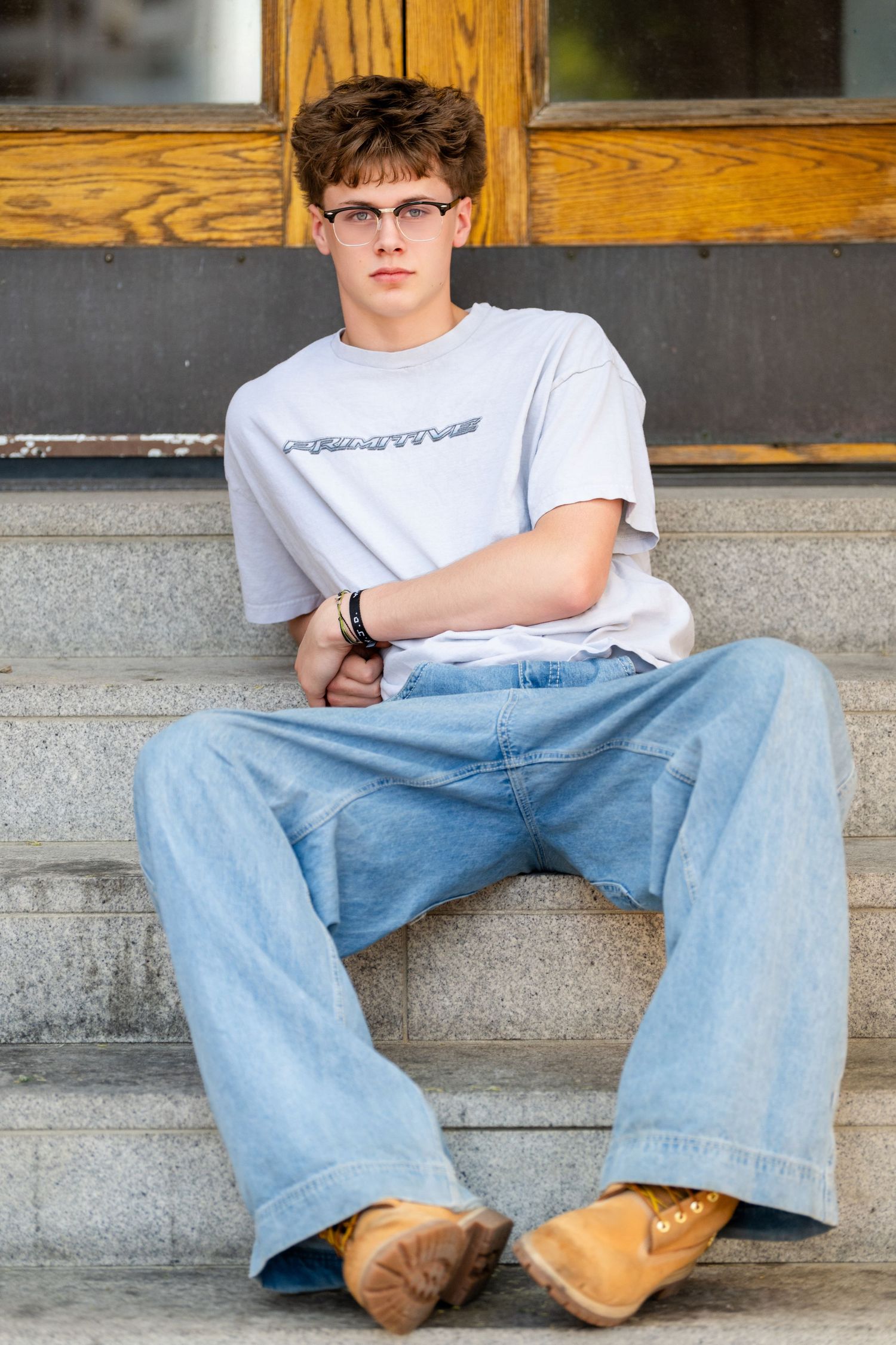 Utah senior boy portrait sitting on stairs in casual outfit during modern senior photography session