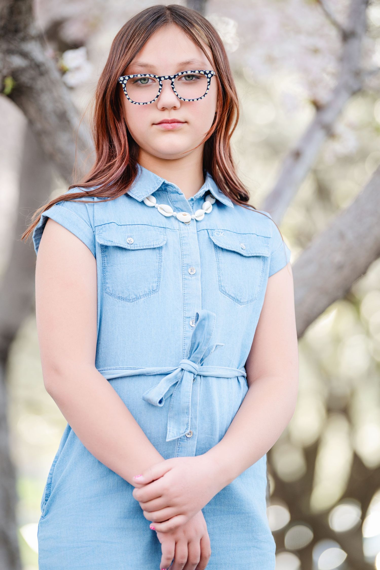 Young girl portrait in blue dress standing outdoors during spring family photography session