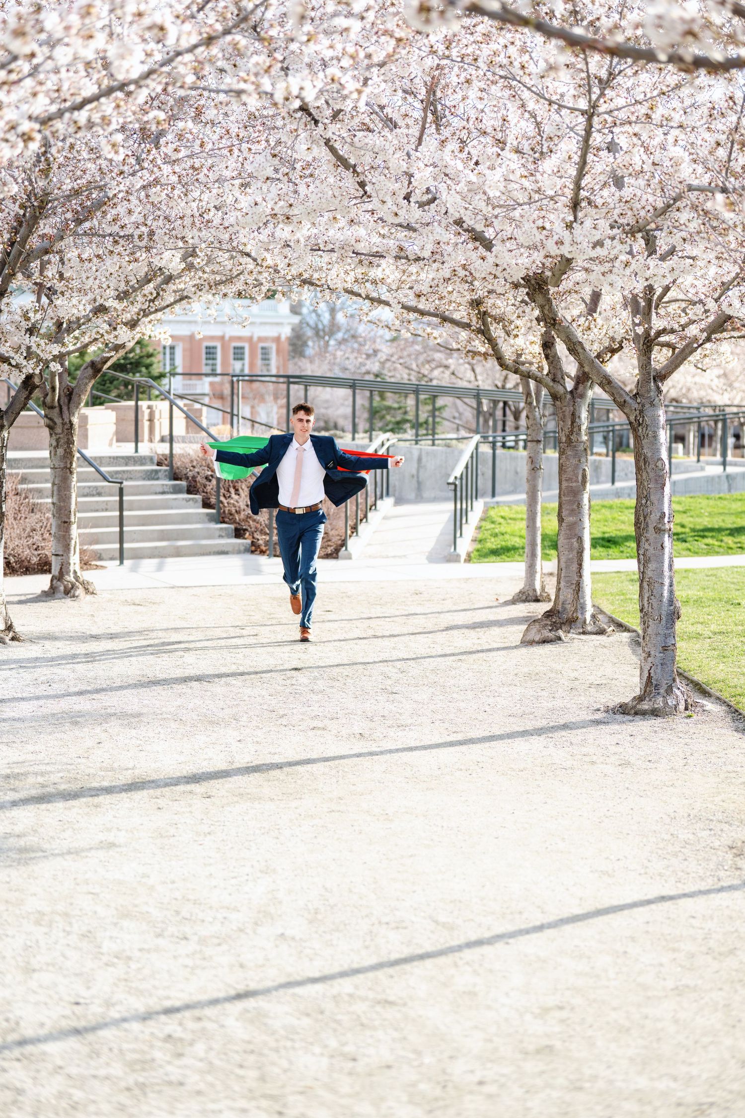 LDS missionary portrait running beneath blossoming spring trees during missionary photography session in Utah