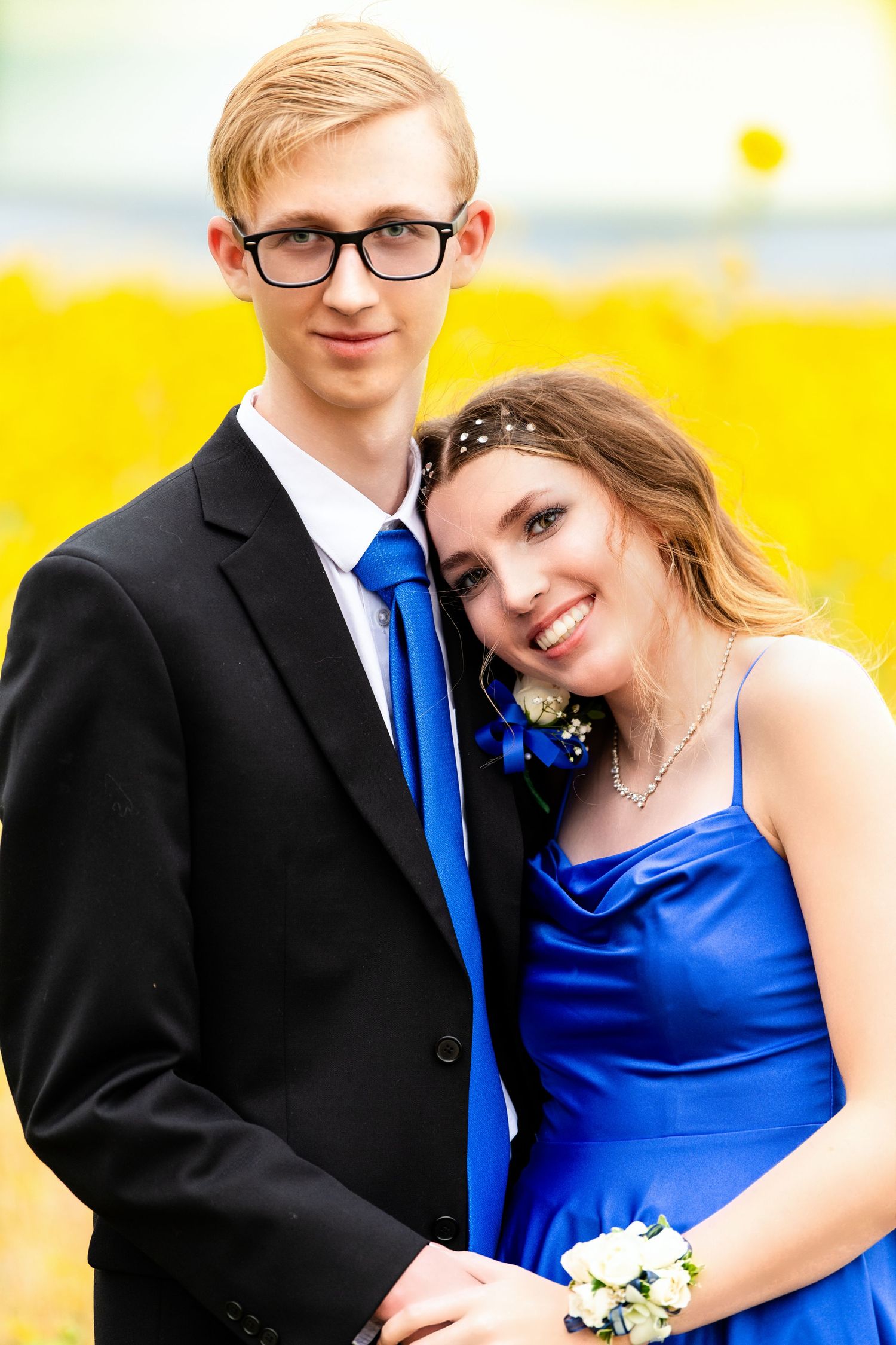 Woods Cross Homecoming couple posing together in formal attire with yellow flower field backdrop