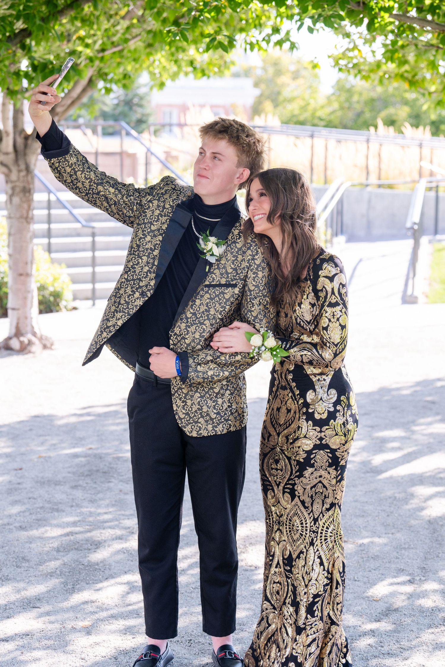 Bountiful High Homecoming couple posing under tree in patterned outfits with relaxed candid feel