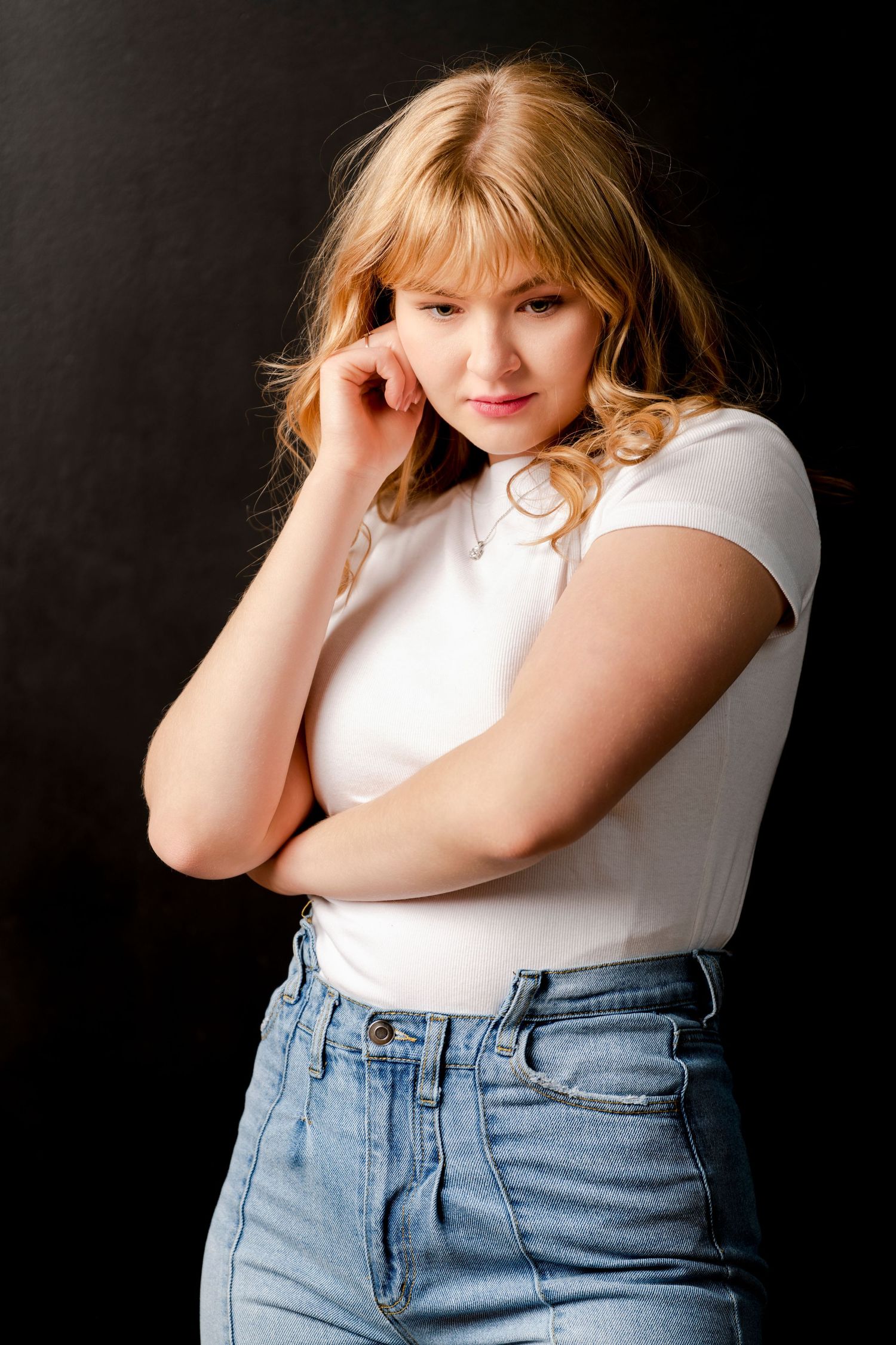 Studio portrait of young woman in white top with soft lighting and thoughtful expression